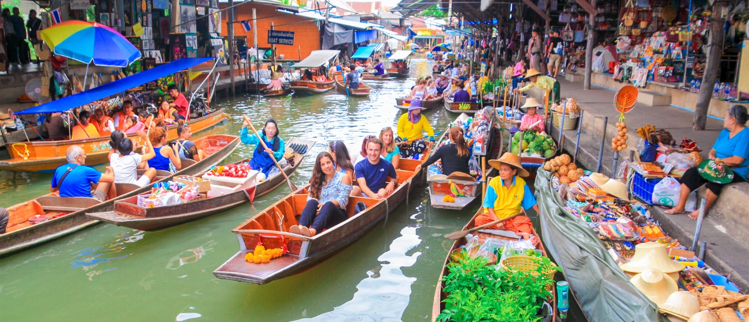 Tourists and vendors navigate crowded boats at the vibrant Amphawa Floating Market in Thailand.