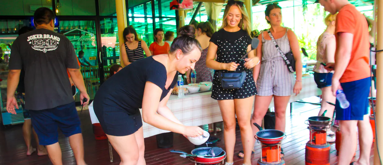 Tourists happily learn to cook local dishes during a cooking lesson in Amaphawa, Thailand.