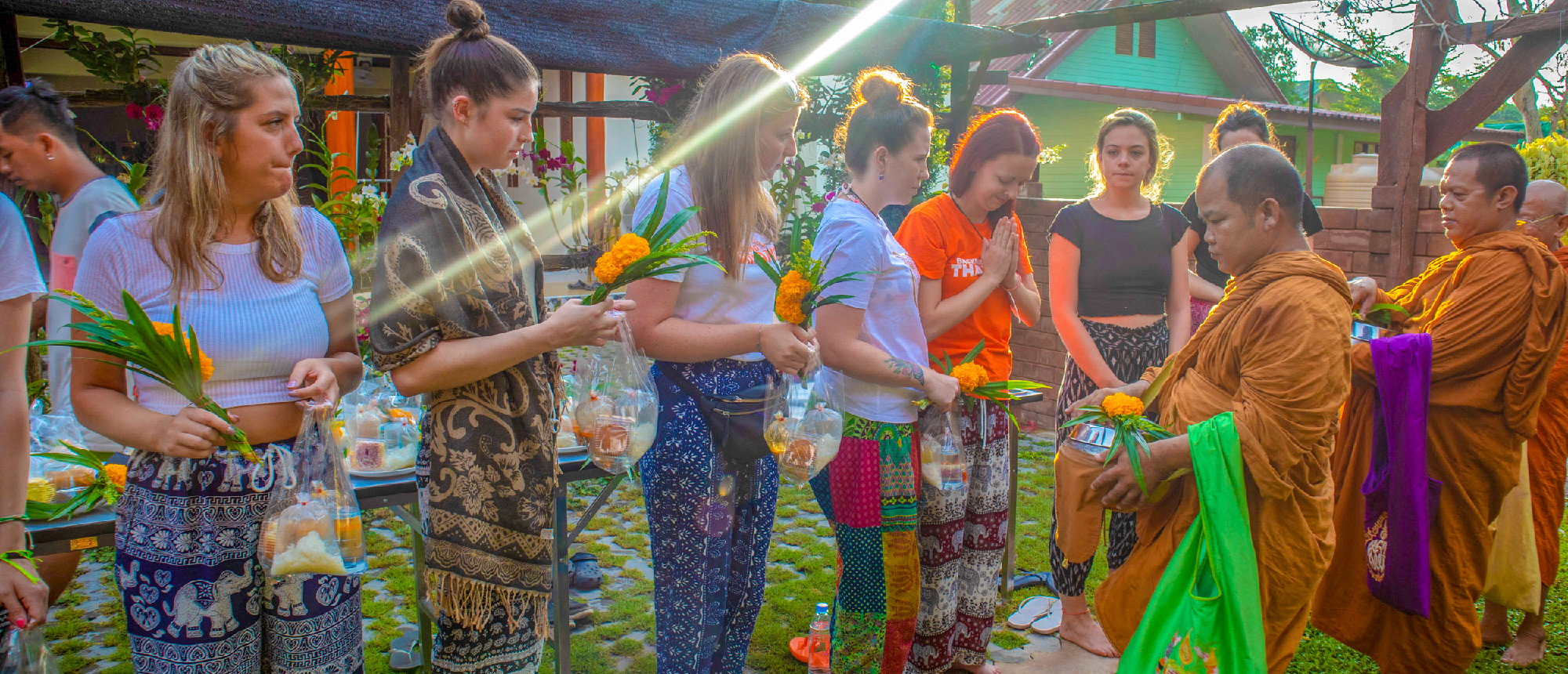 Tourists respectfully offer food and flowers to Buddhist monks during a morning merit ceremony in Amaphawa, Thailand.