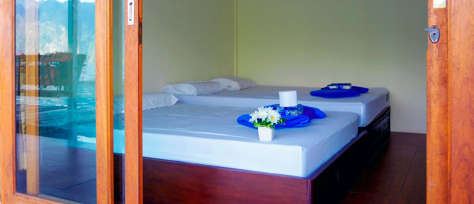 Bright room in a Khao Sok floating bungalow with two single beds and a lake view.