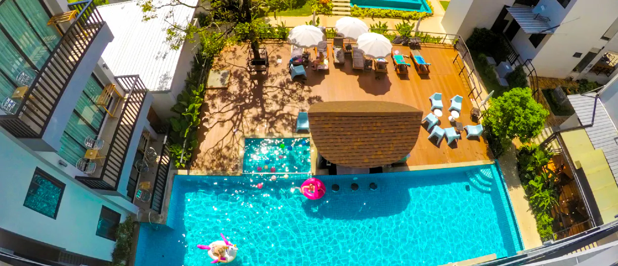 Aerial view of a vibrant resort pool in Krabi, Thailand, with guests relaxing on floats.