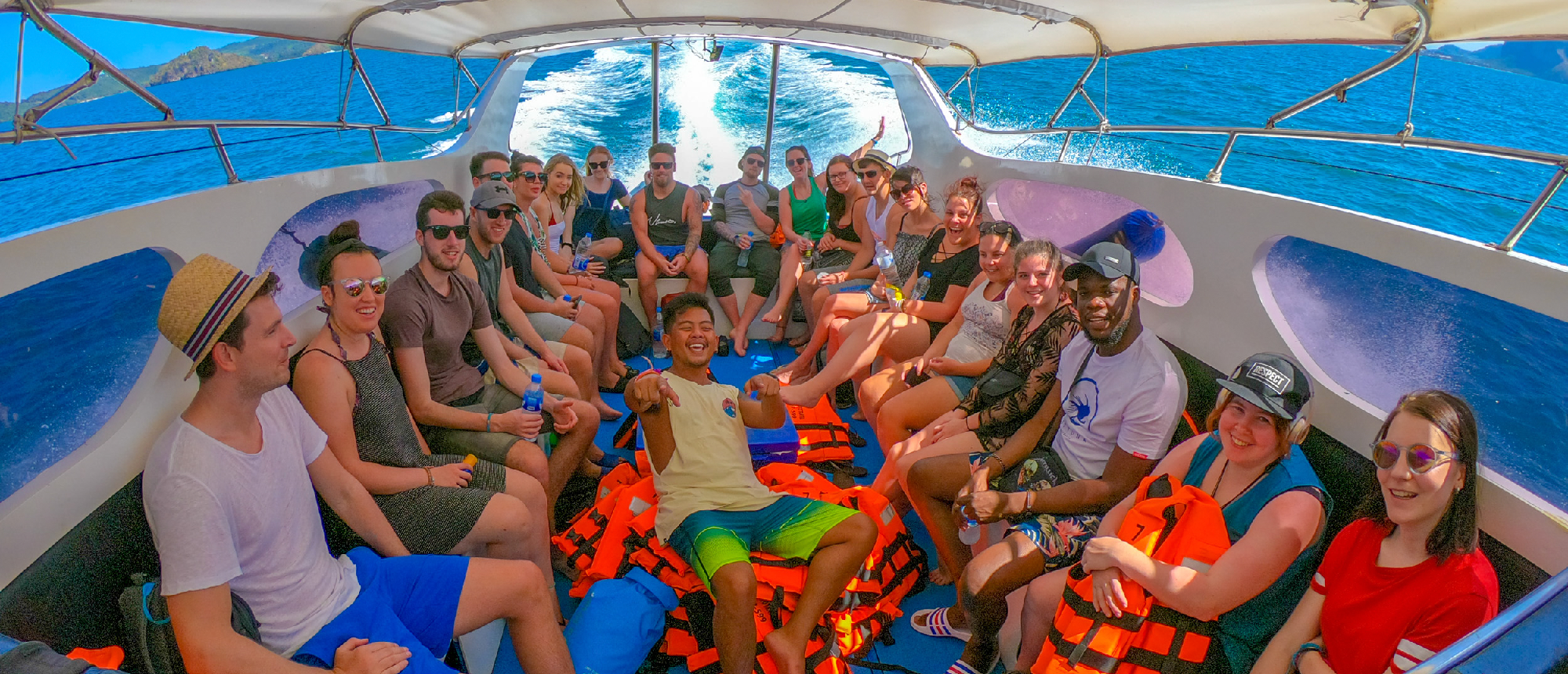 Excited backpackers on a speed boat, cruising through the clear blue waters of Koh Phi Phi, Thailand.