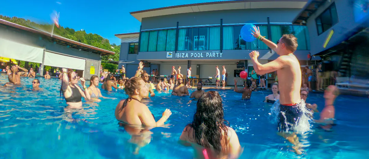 Travellers splash and play in a lively Ibiza Pool Party pool at Koh Phi Phi, Thailand.