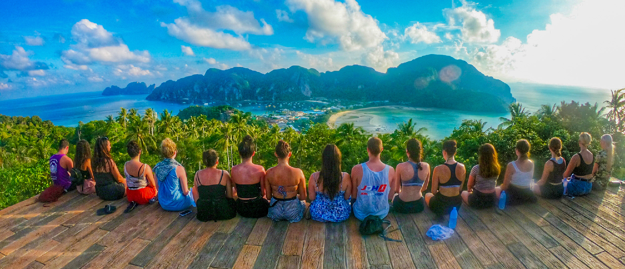Travelers sit on a viewpoint, enjoying the stunning panoramic view of Koh Phi Phi's bays and islands.