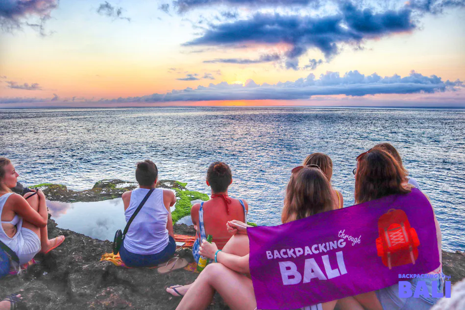 Backpackers watch a beautiful sunset over the ocean from rocky cliffs in Nusa Lembongan, Bali.