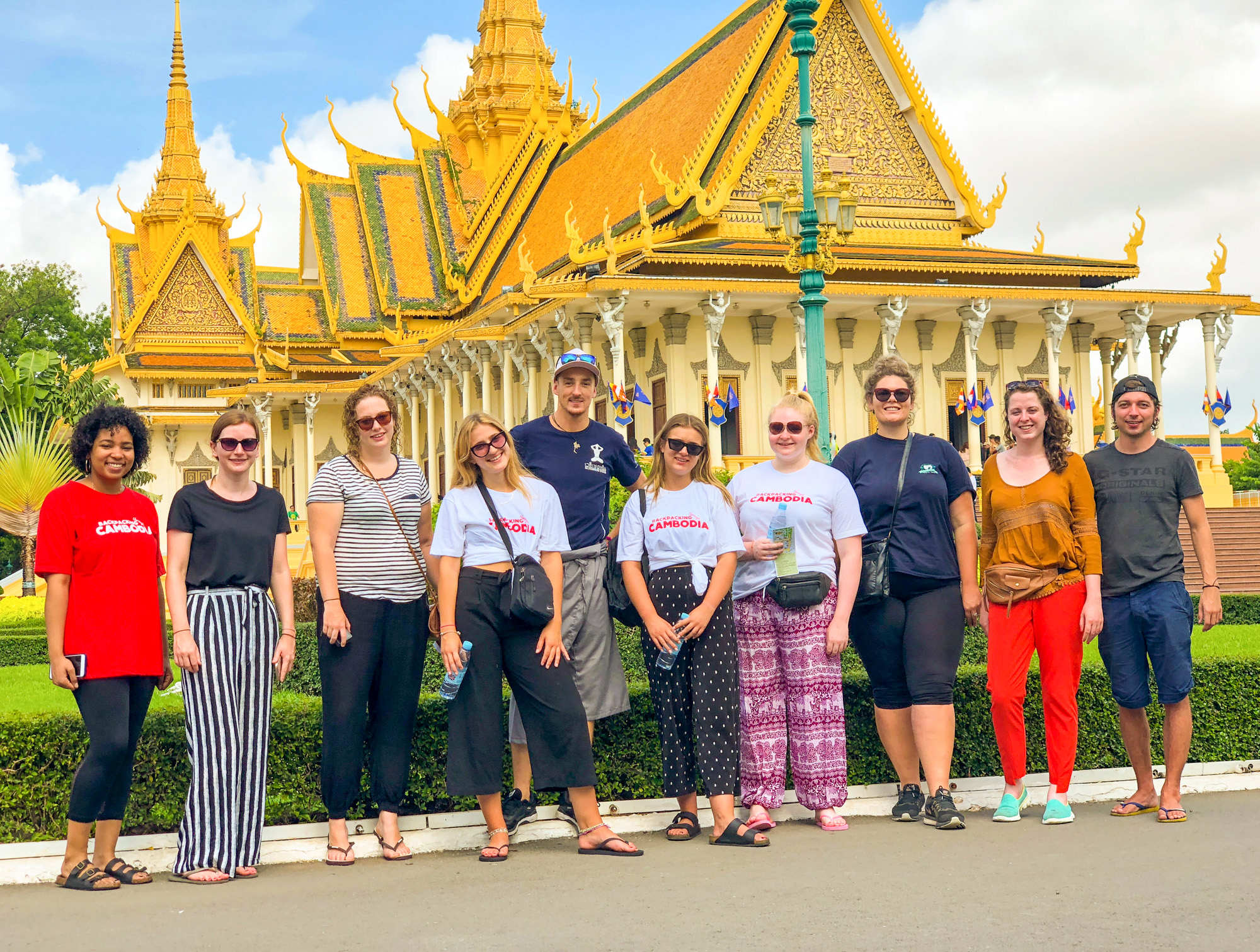 A group of happy backpackers posing in front of the Royal Palace in Phnom Penh, Cambodia.