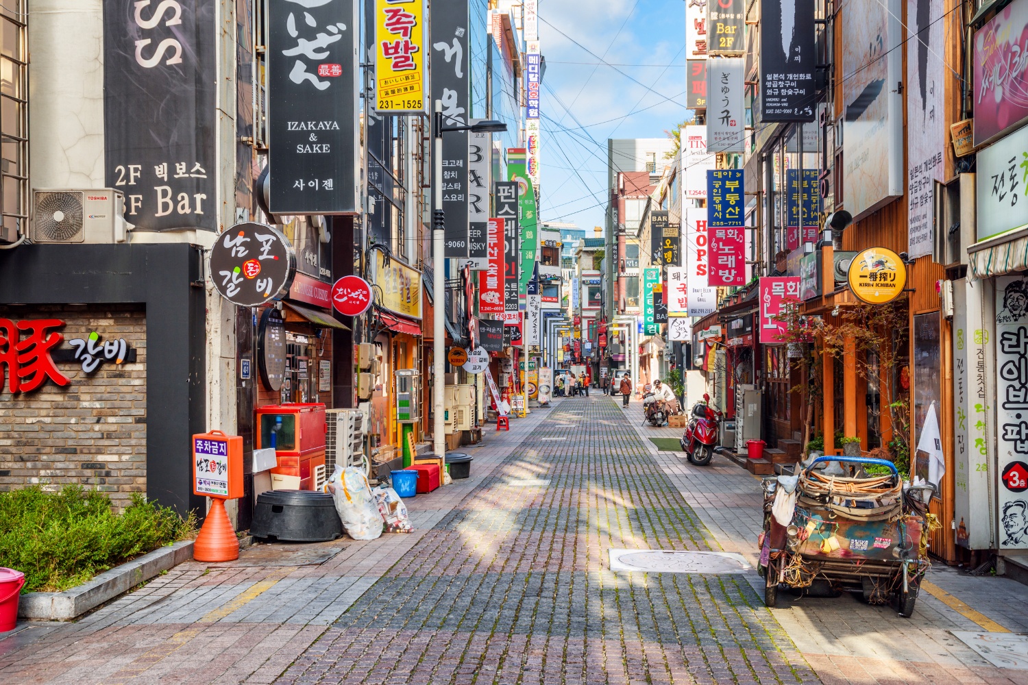 A bustling street in Itaewon, South Korea, with shops, restaurants, and colorful signs.