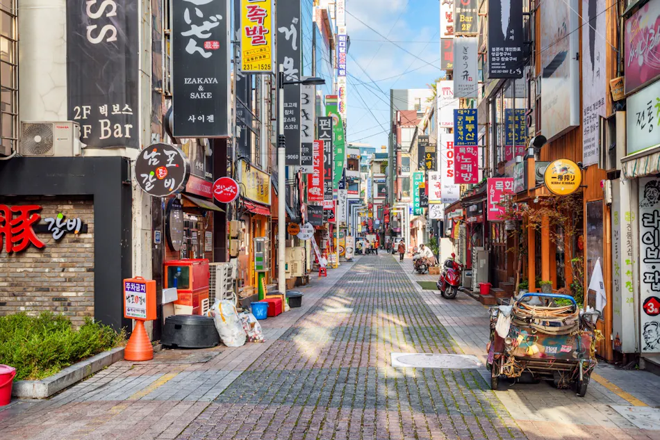 A bustling street in Itaewon, South Korea, with shops, restaurants, and colorful signs.