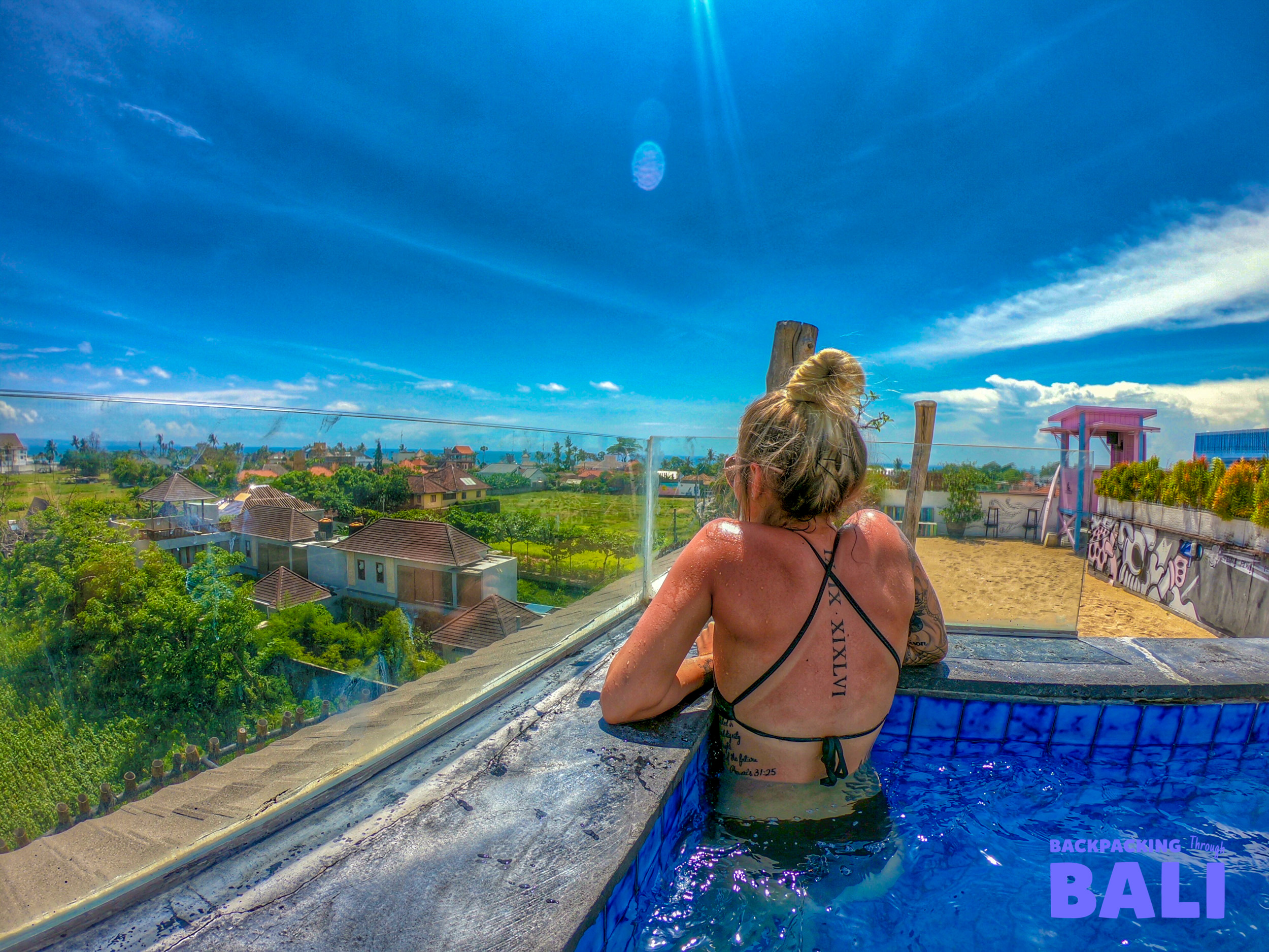 A woman relaxes in a rooftop pool, enjoying the sunny views of Canggu, Bali.