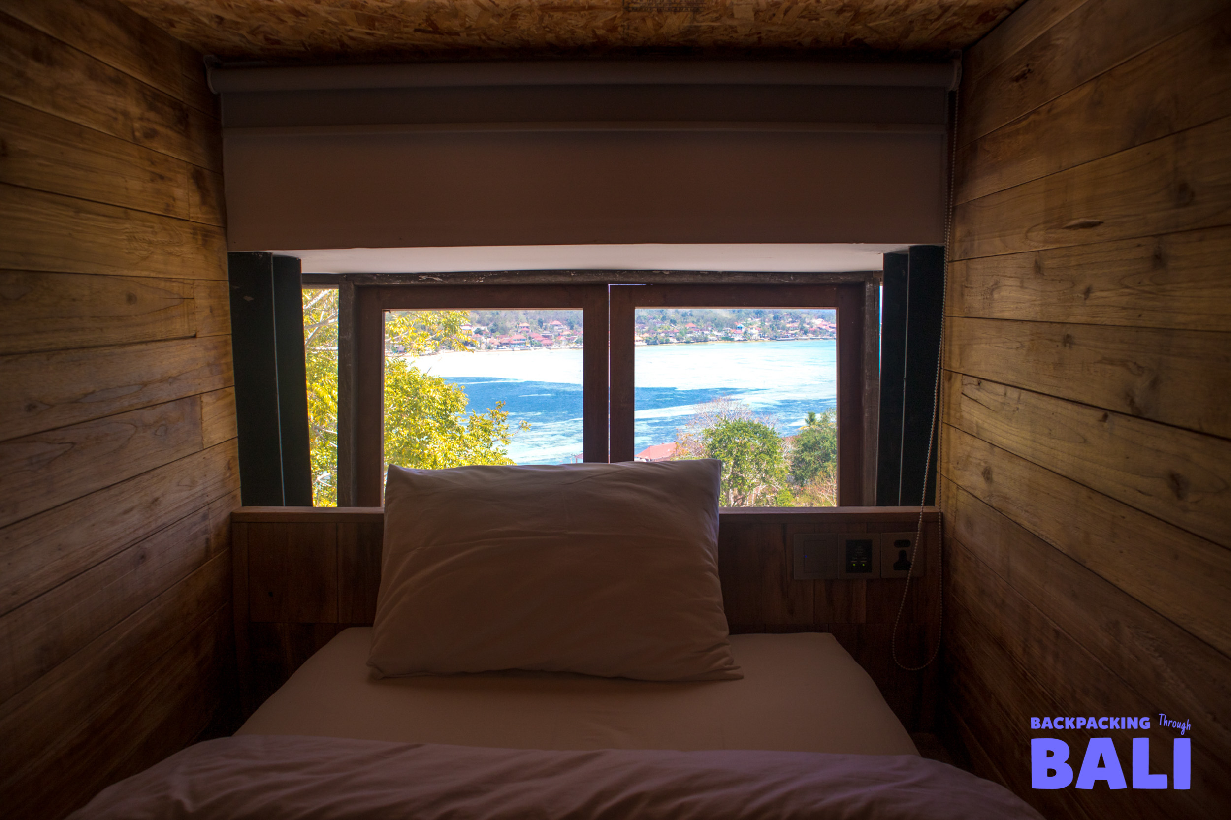 A cozy wooden room with a comfortable bed and a stunning ocean view from Nusa Lembongan.