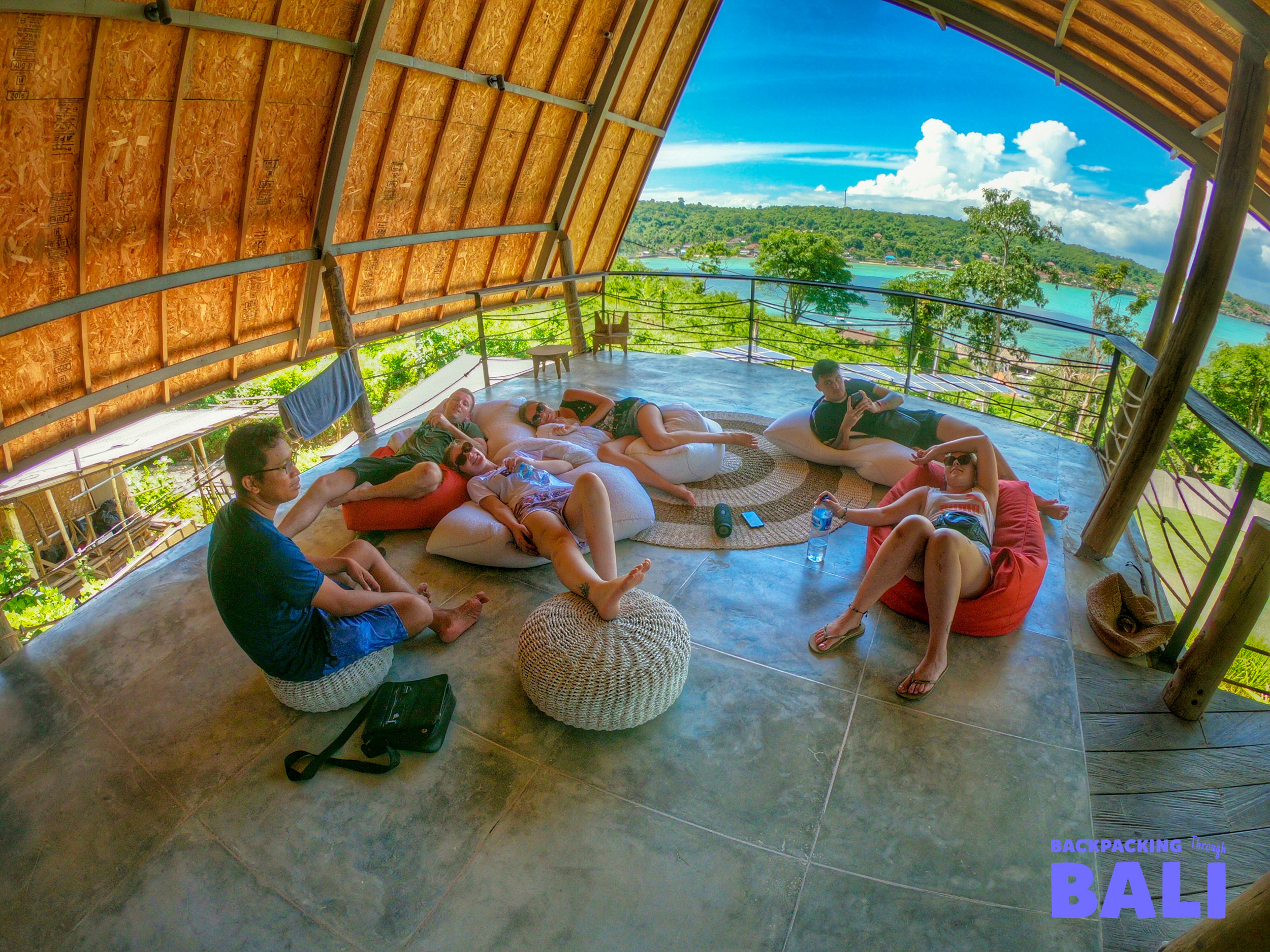 Travelers relax on bean bags on a terrace overlooking the beautiful bay of Nusa Lembongan.