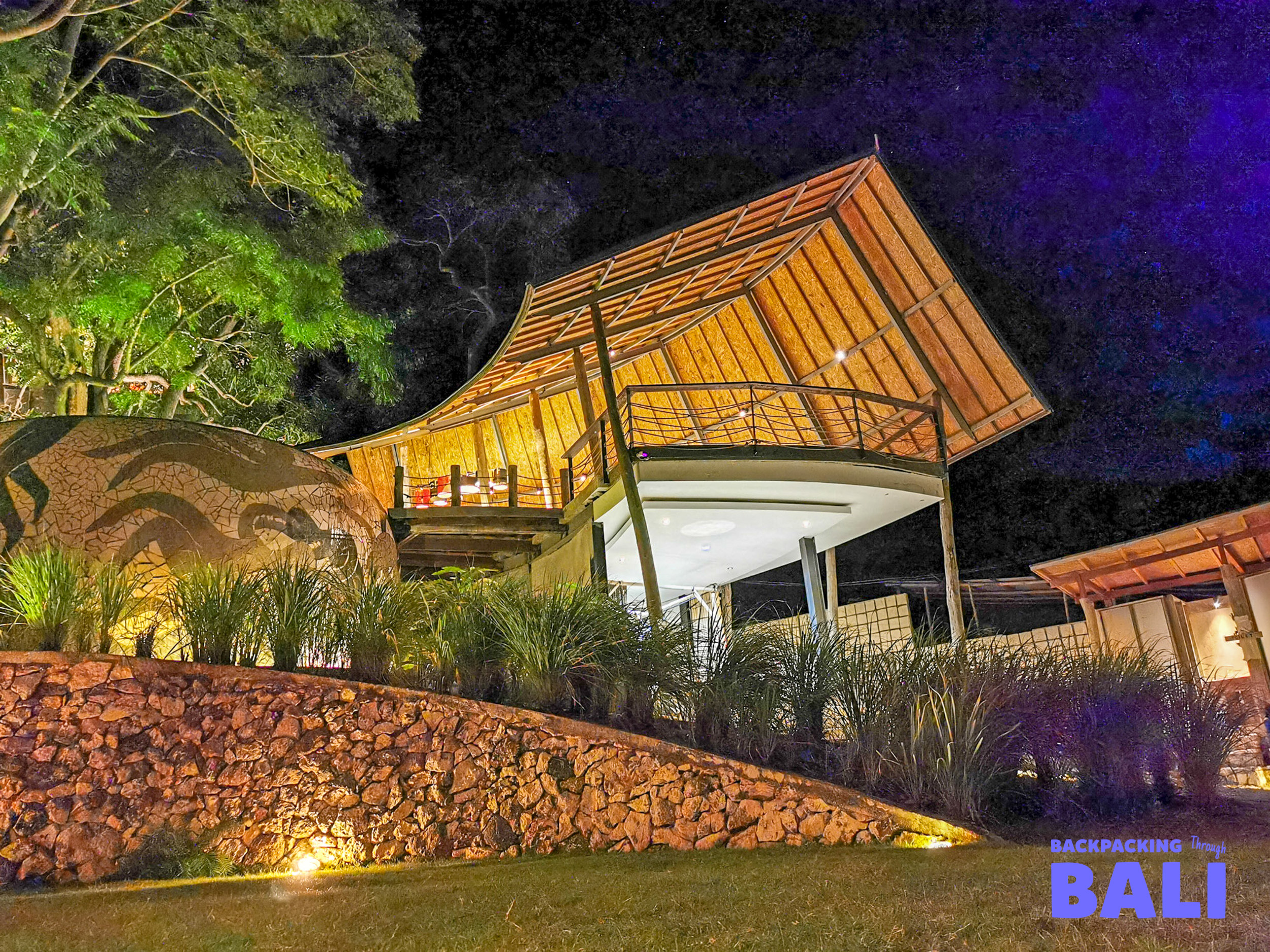A beautiful tropical resort building with a curved roof illuminated at night on Nusa Lembongan.