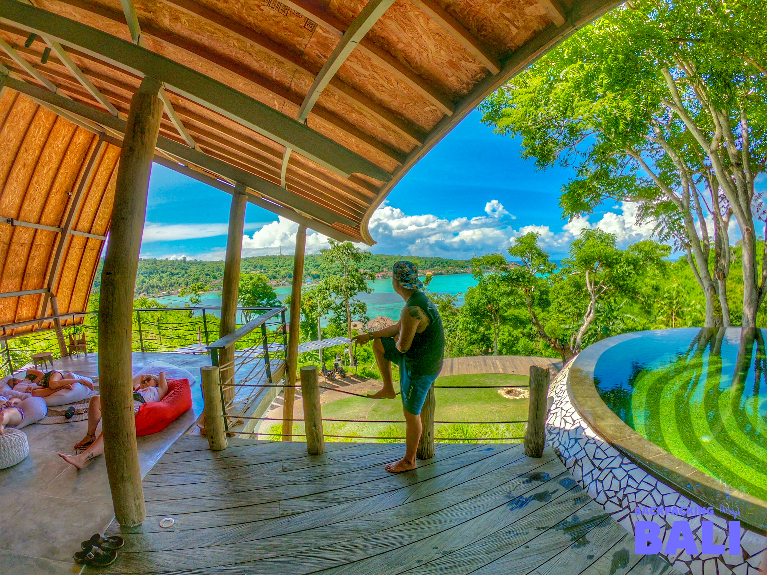 Enjoying the stunning tropical bay view from a wooden deck with an infinity pool in Nusa Lembongan.