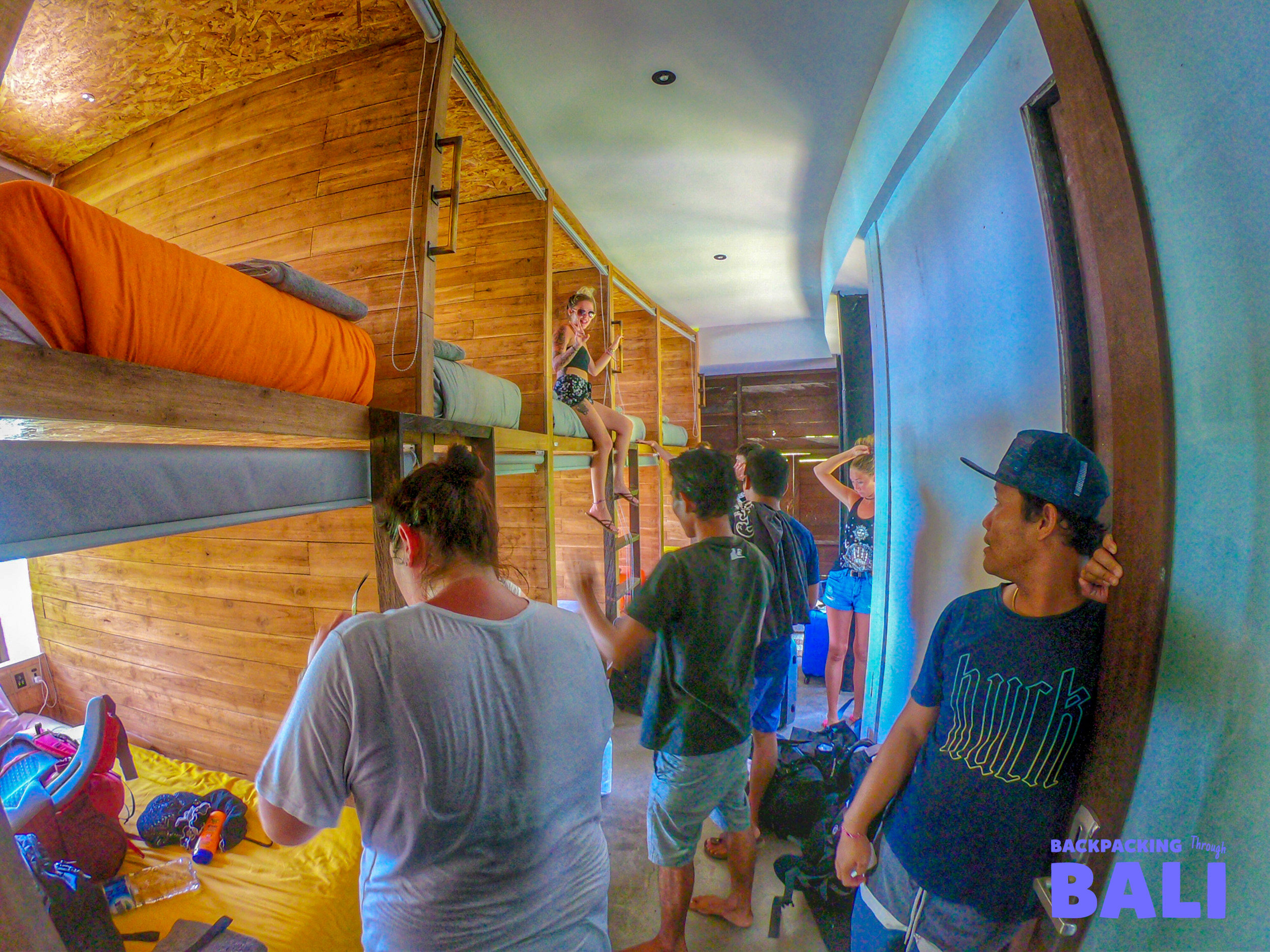 Young backpackers settle into their wooden capsule bunk beds in a hostel dorm on Nusa Lembongan.
