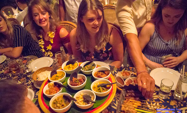 Backpacking group sharing Balinese dinner together at a long table