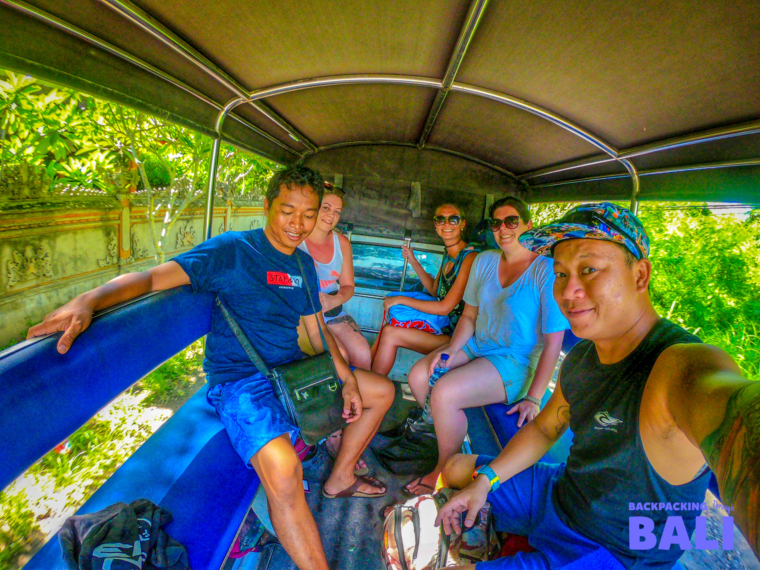 Happy backpackers enjoy an open-air shuttle ride, exploring Nusa Lembongan's tropical beauty.