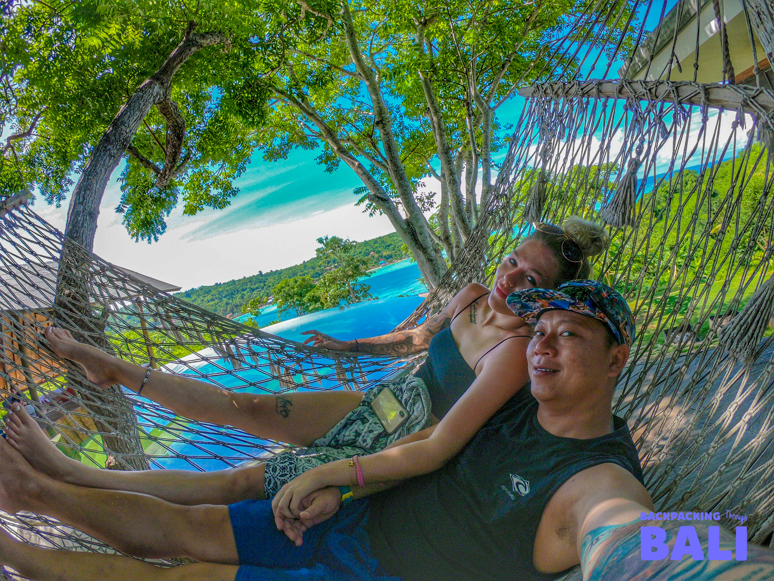 Smiling couple relaxing in a hammock overlooking the beautiful turquoise waters of Nusa Lembongan.