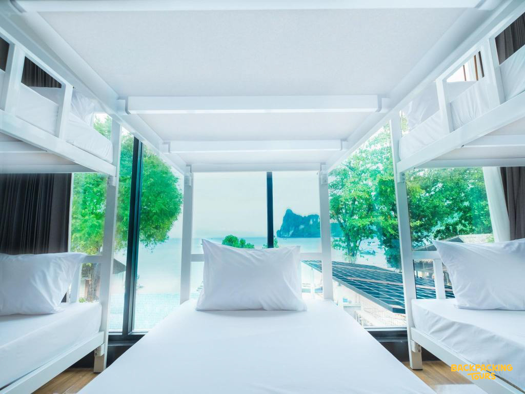 Clean white bunk beds in a bright Koh Phi Phi hostel room with a stunning tropical ocean view.