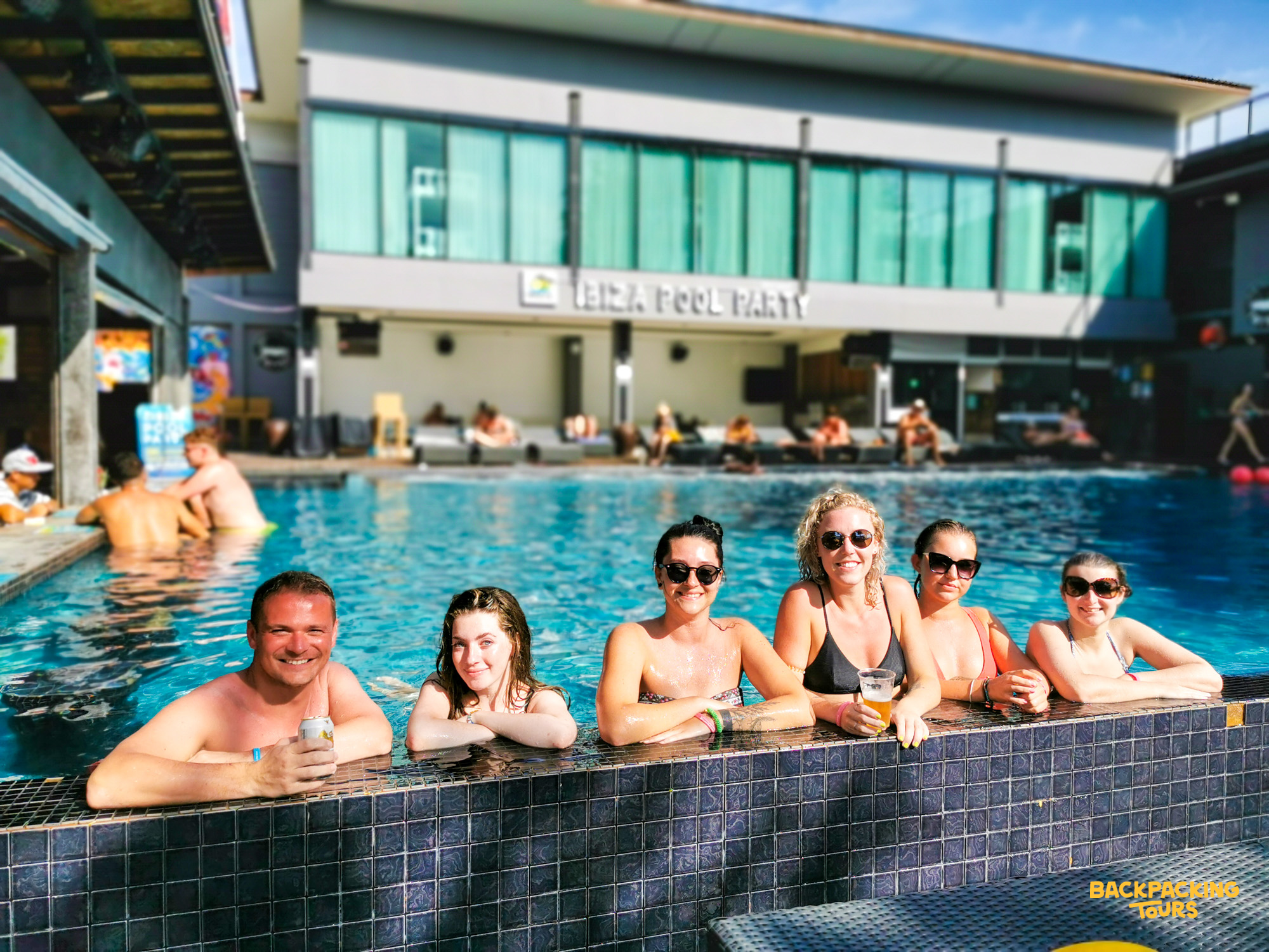 Six happy backpackers enjoying a lively pool party at a hostel in Koh Phi Phi.