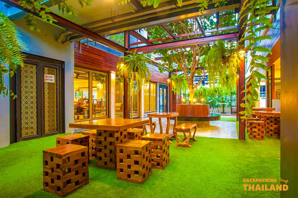 Inviting outdoor patio with wooden furniture and lush greenery at a Bangkok accommodation.