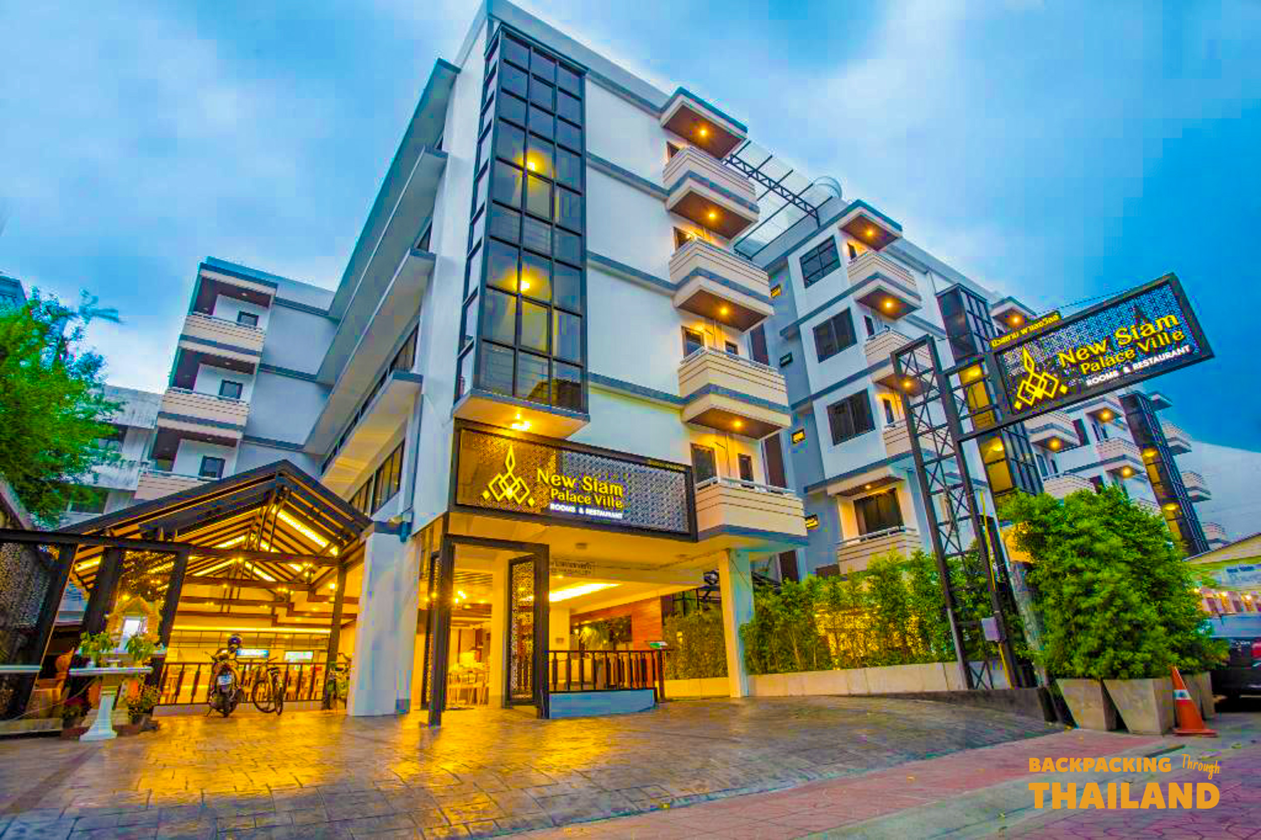 New Siam Palace Ville, a modern hotel building with warm lighting and balconies in Bangkok.