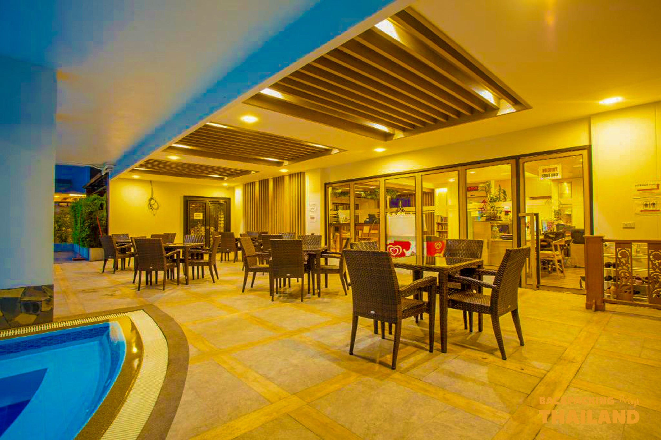 An inviting outdoor restaurant with empty tables next to a small pool at a Bangkok hotel.