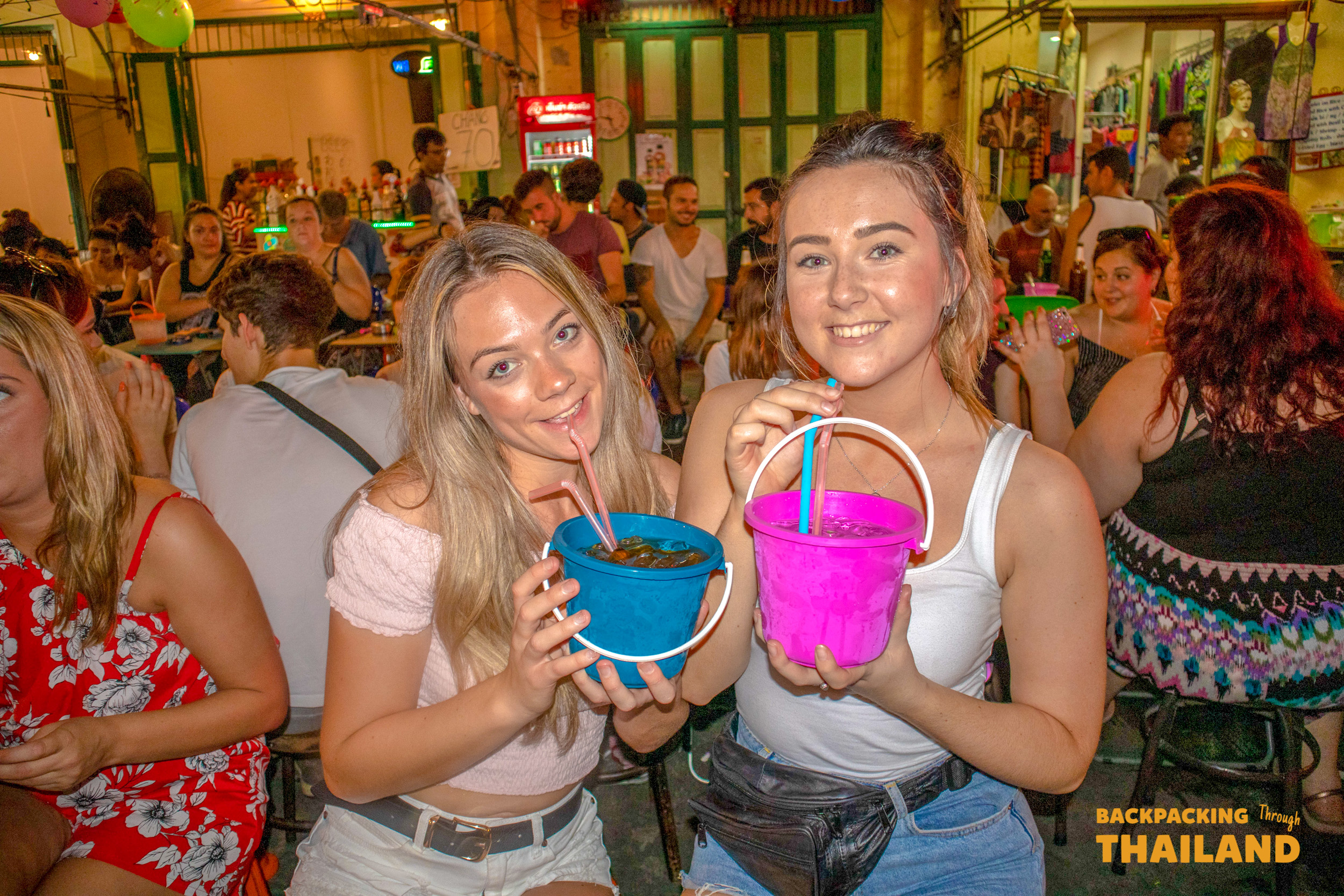 Two girls holding drink buckets at Khao San Road party.