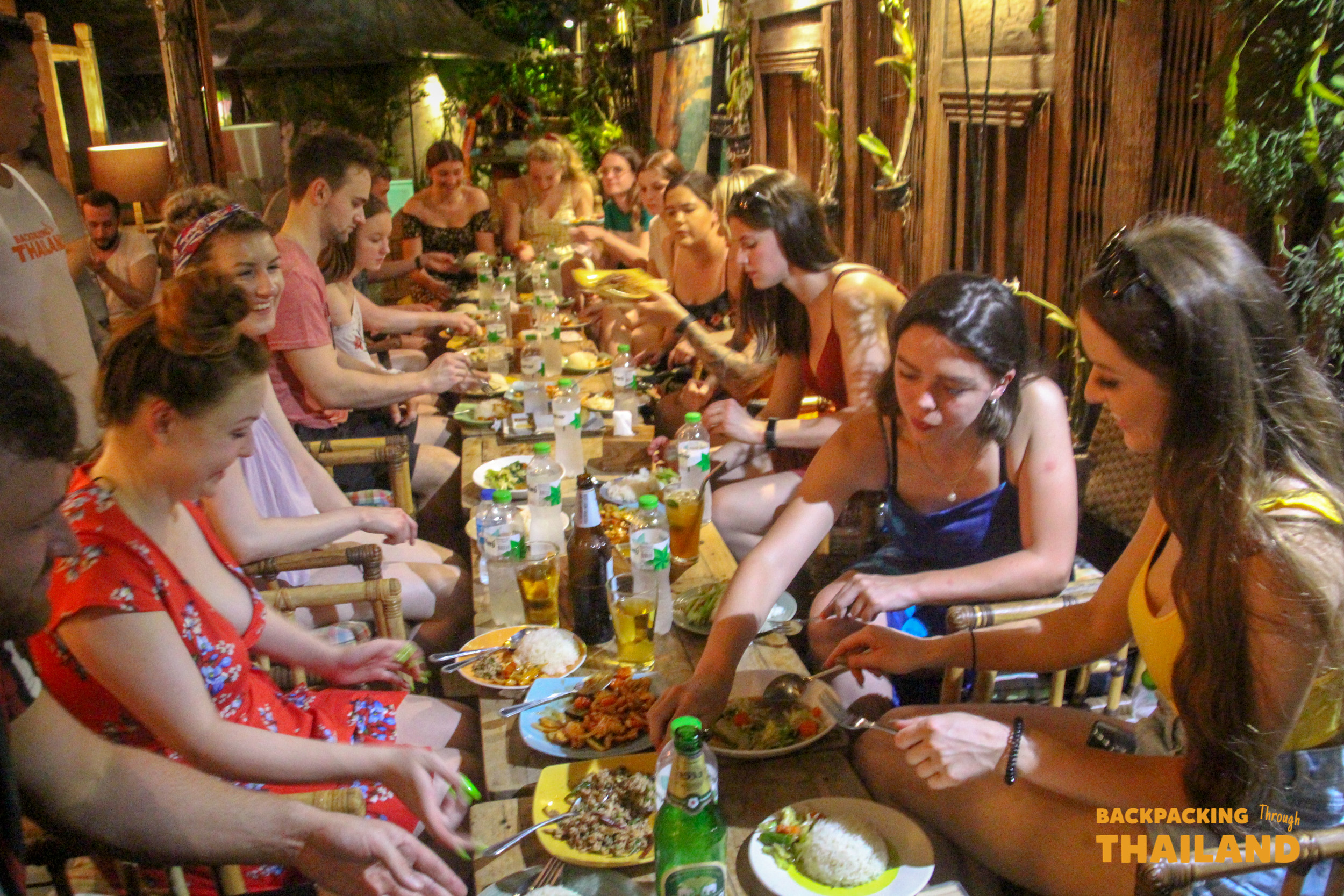 Backpackers enjoy a lively communal dinner with traditional Thai food at a restaurant on Khao San Road.