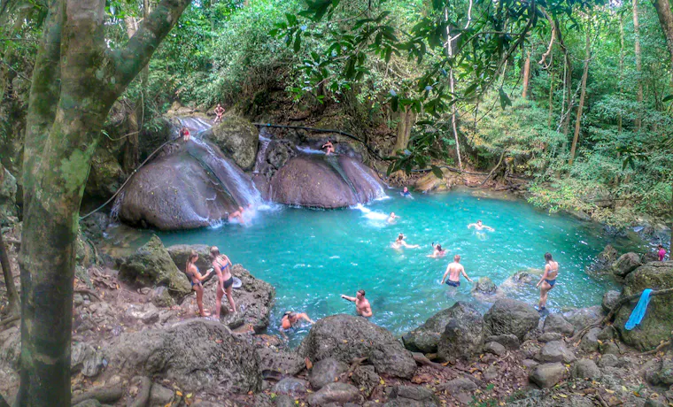 People swim and relax in the refreshing emerald pools of Erawan National Park waterfalls, Thailand.