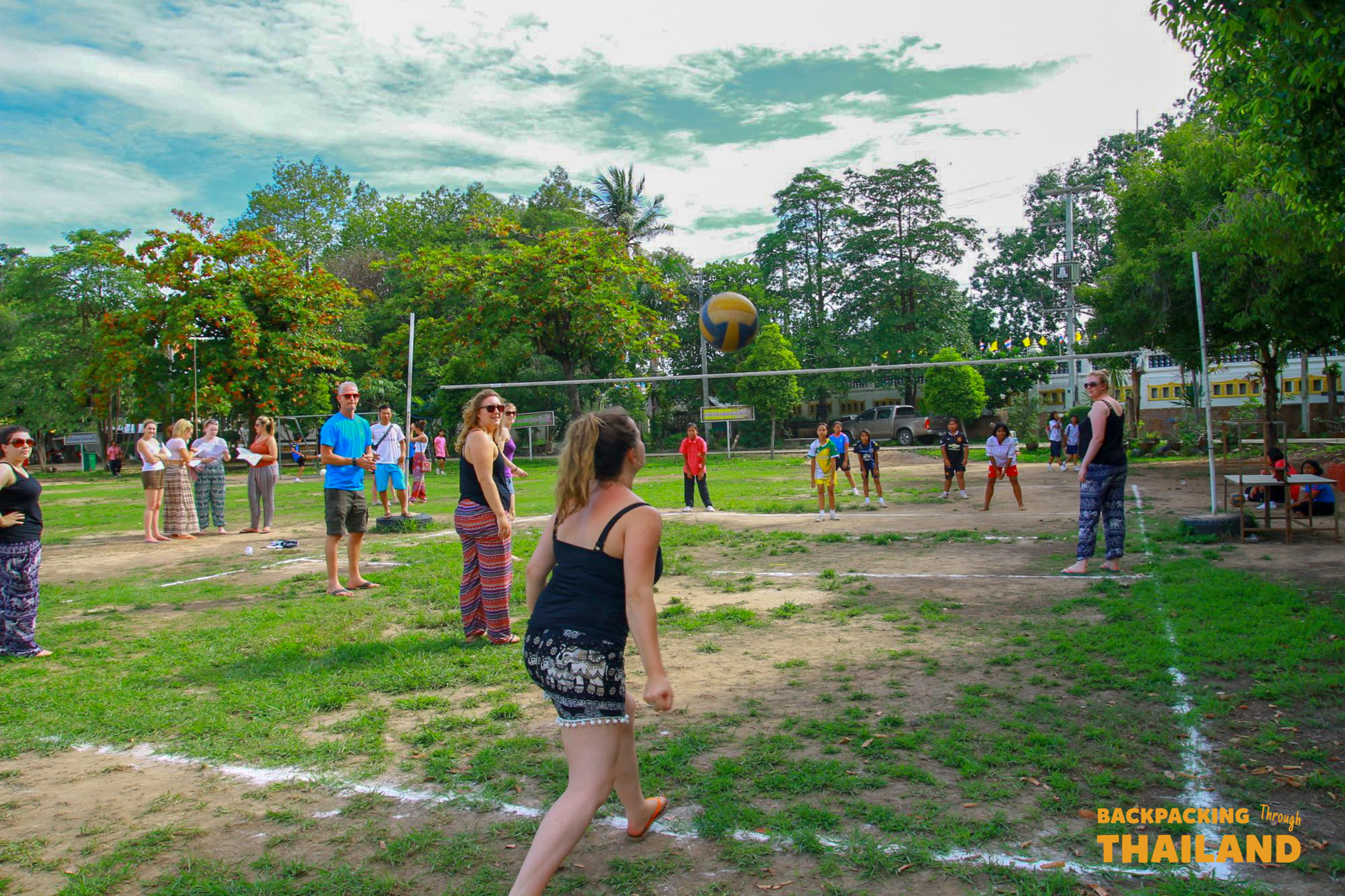 Backpackers and local students enjoy a friendly game of volleyball at a Thai school.
