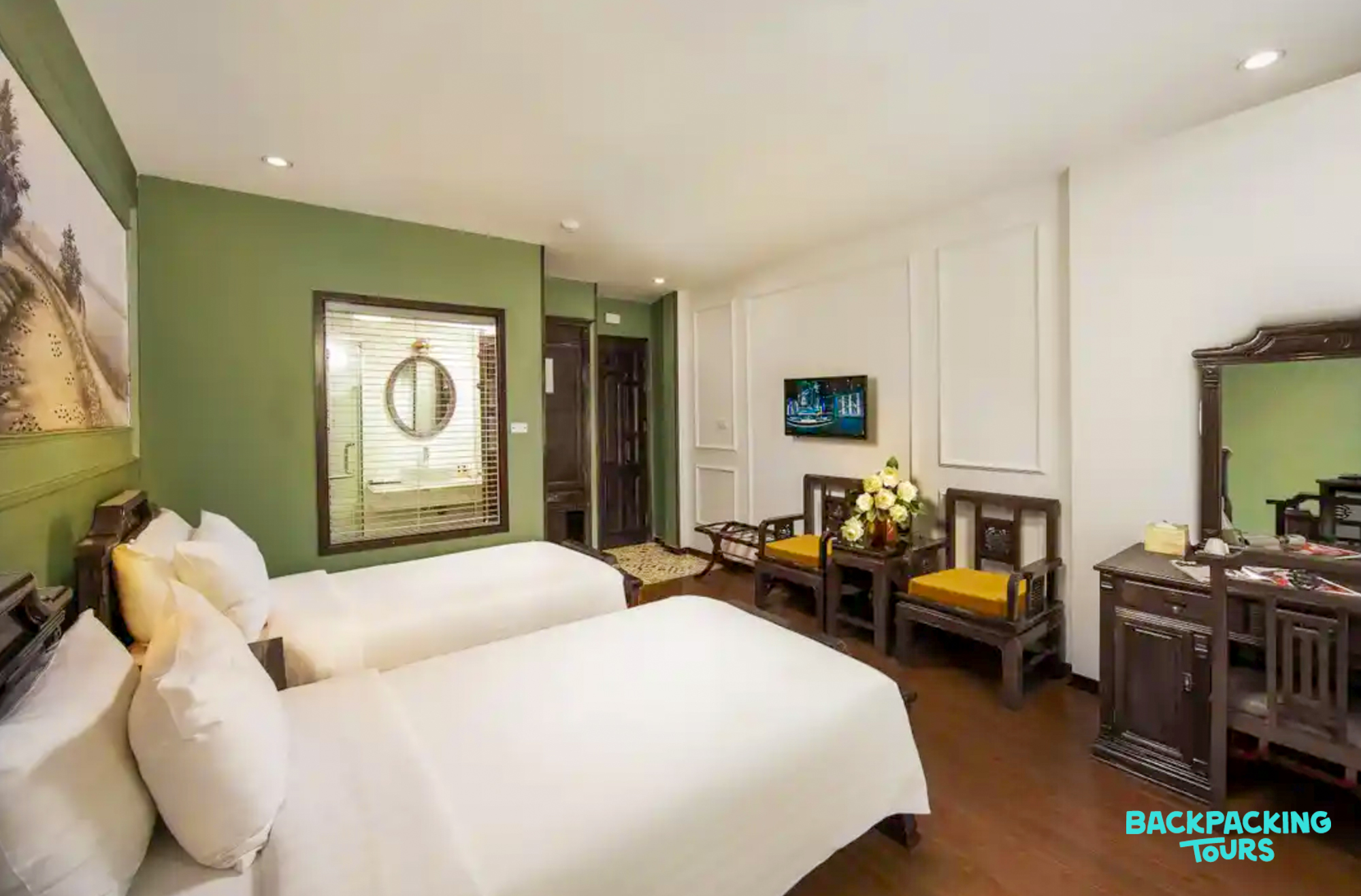 A comfortable hotel room in Hanoi with two single beds and traditional wooden furniture.