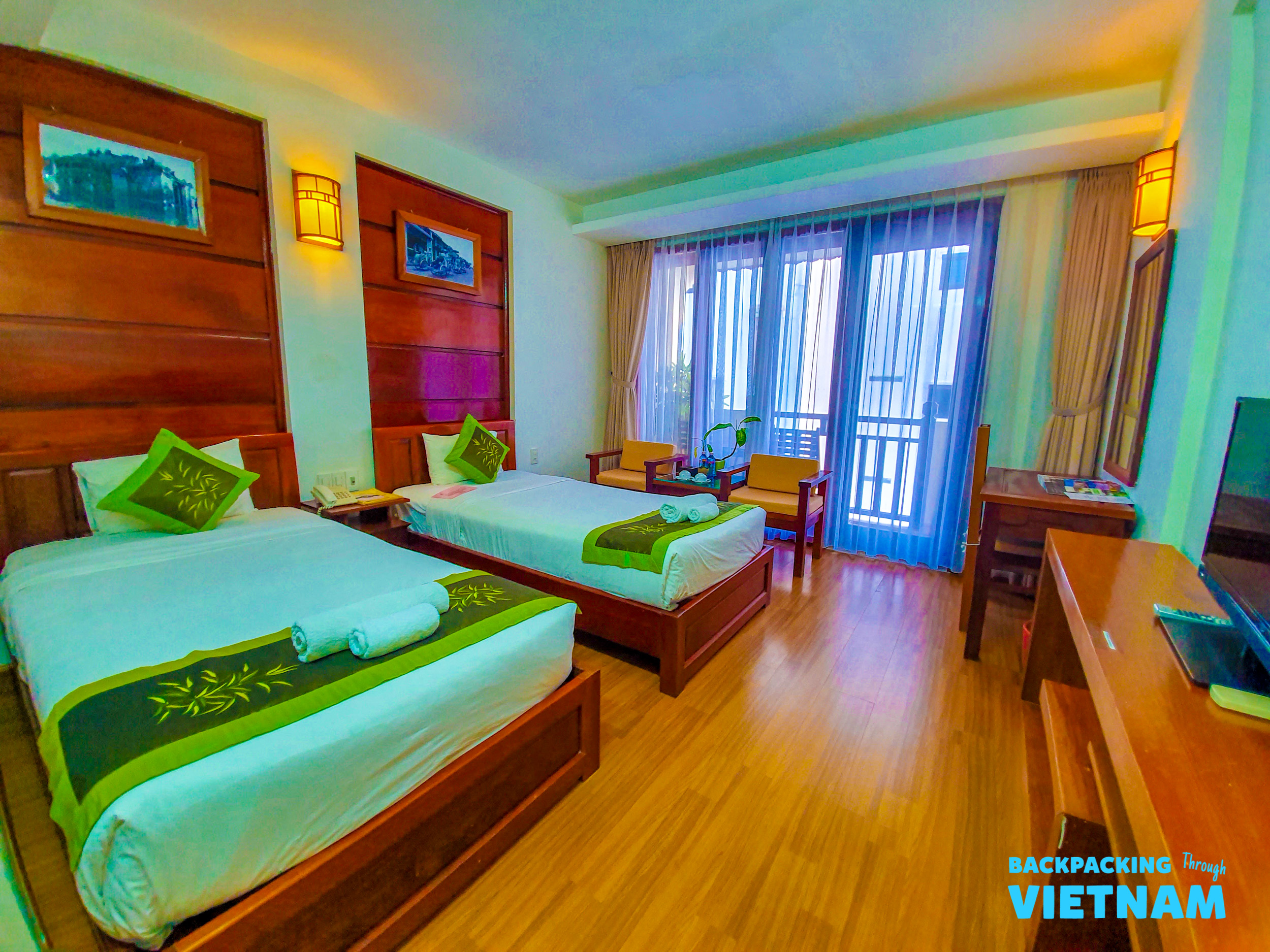 A cozy twin room in Hoi An with warm wooden accents, comfortable beds, and a sunny balcony.