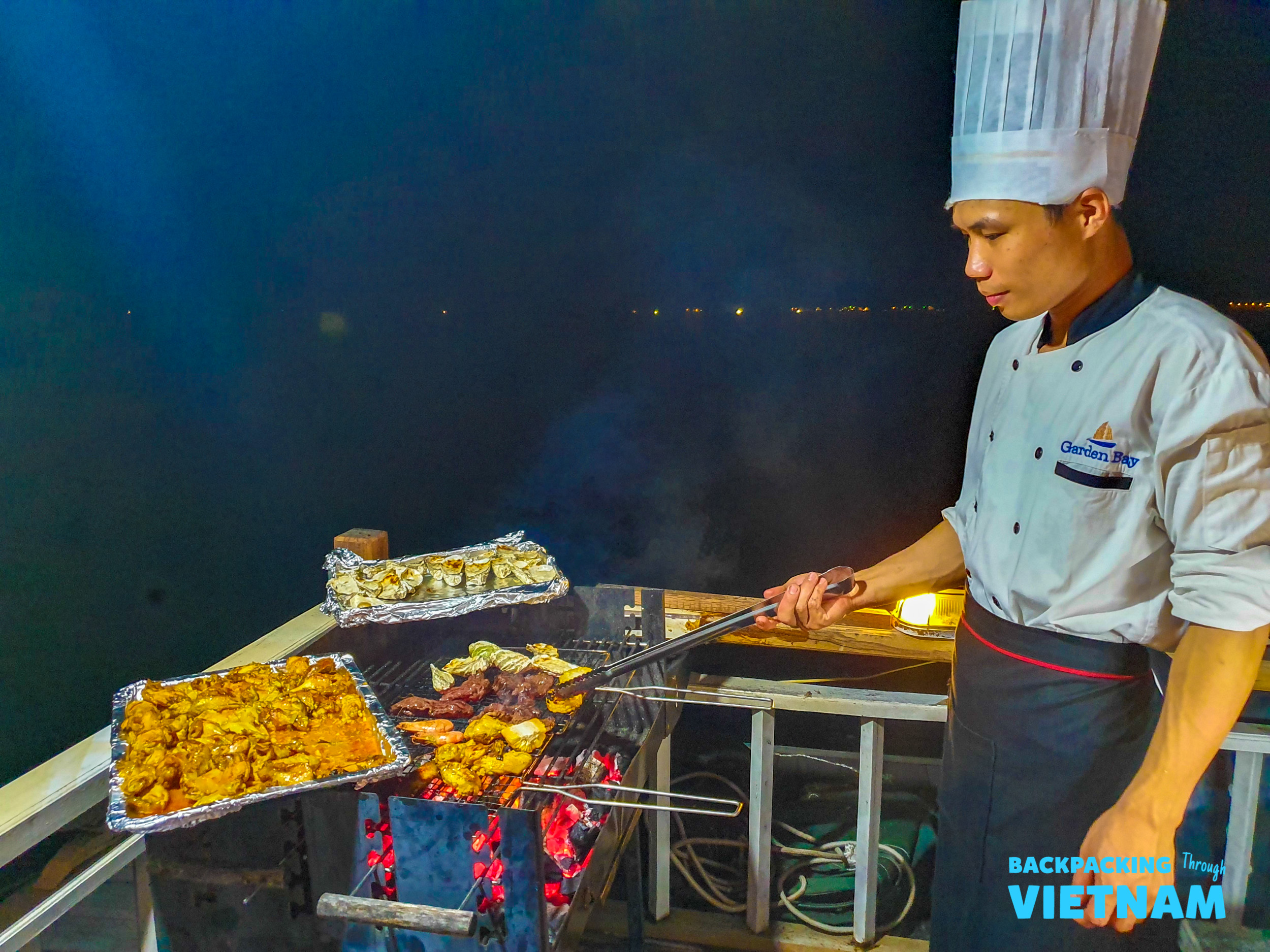 A chef cooks a delicious barbecue dinner on a boat deck at night in Halong Bay.
