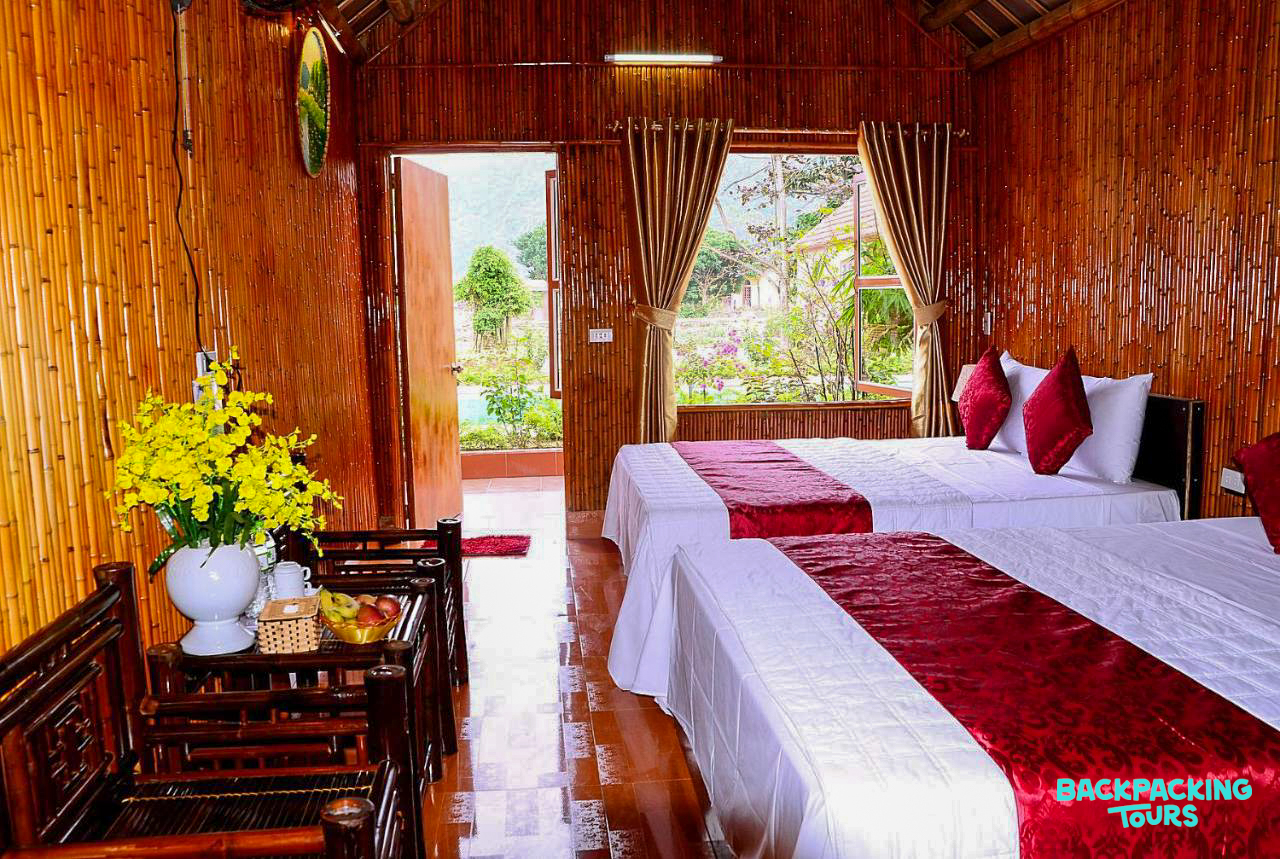 Inviting resort room in Tam Coc featuring natural bamboo walls, comfortable beds, and a lush garden view.