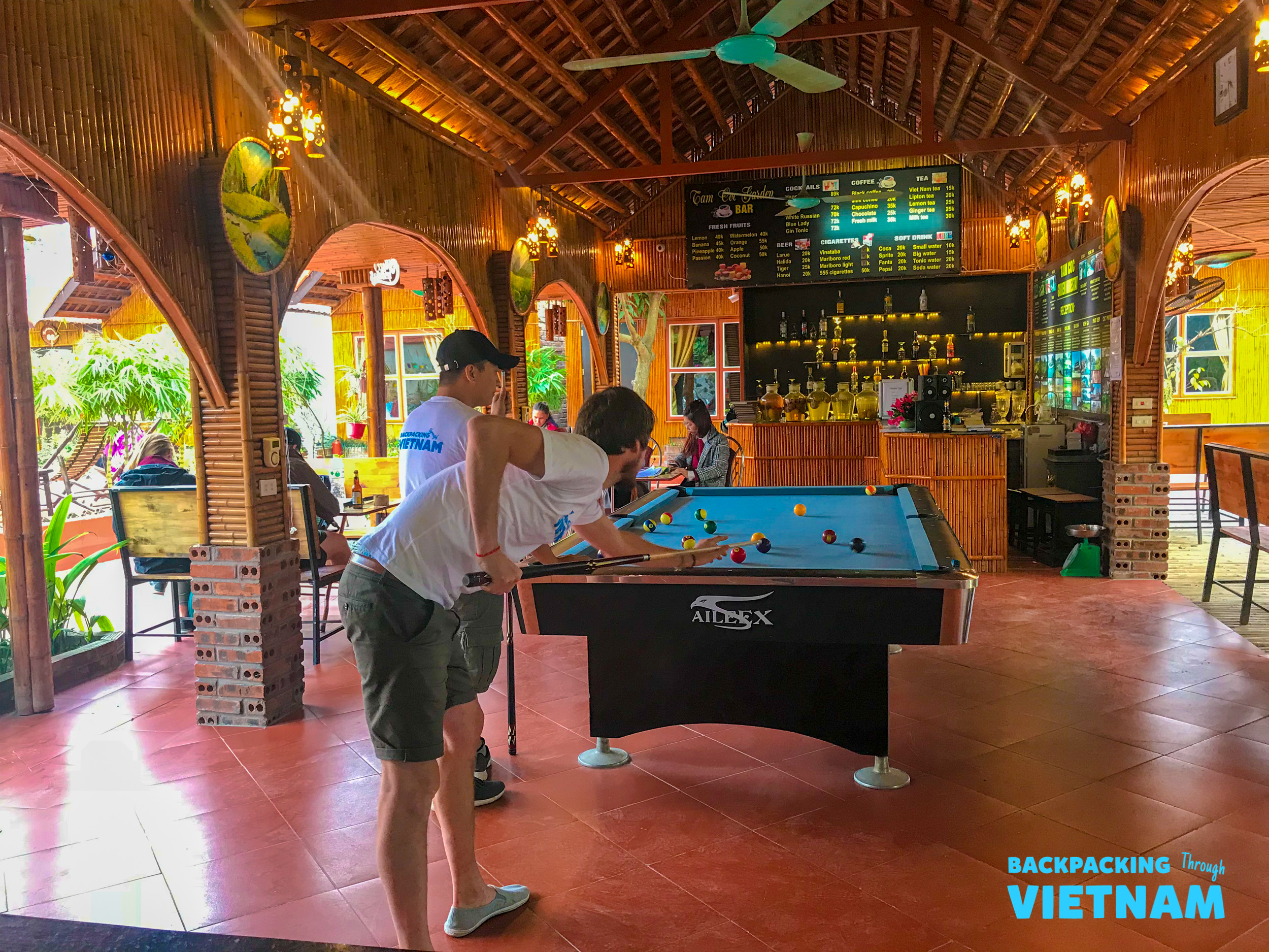 Two men enjoy a game of pool in a lively bar at their Tam Coc accommodation.