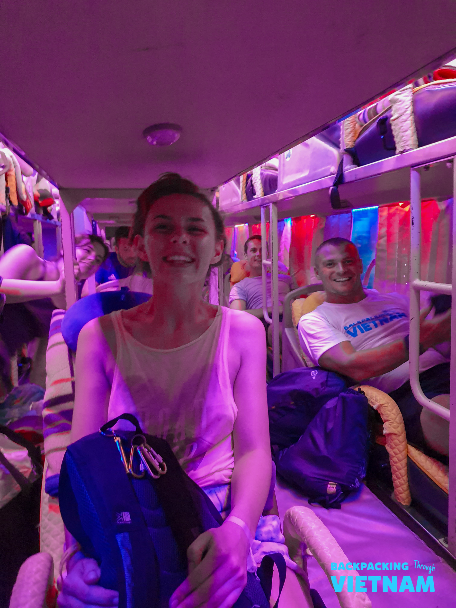 Smiling travelers relax in their bunks on a colorful overnight sleeper bus in Vietnam.