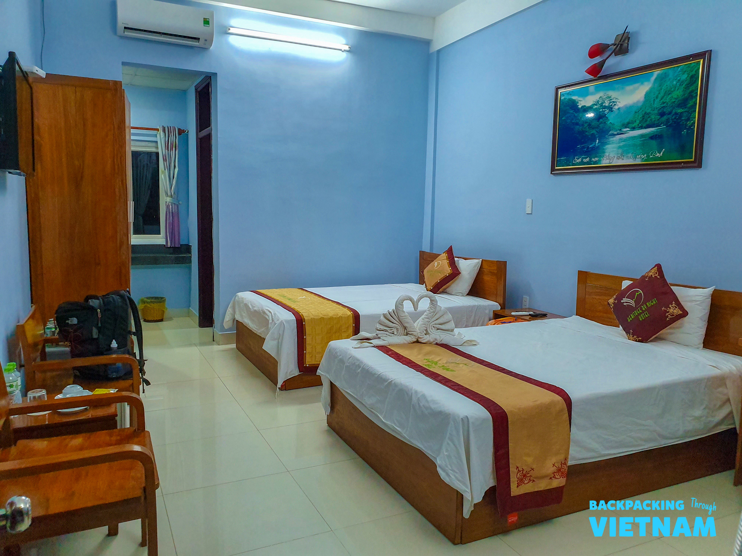 A comfortable twin room with blue walls and wooden furniture, ready for guests in Phong Nha.