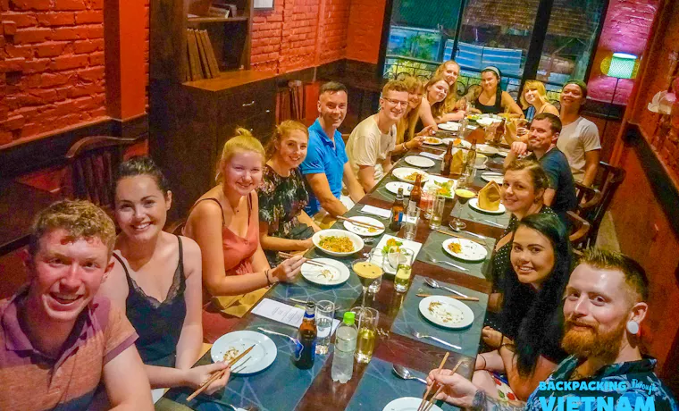A group of happy young travelers enjoying a delicious welcoming dinner together in Hanoi, Vietnam.