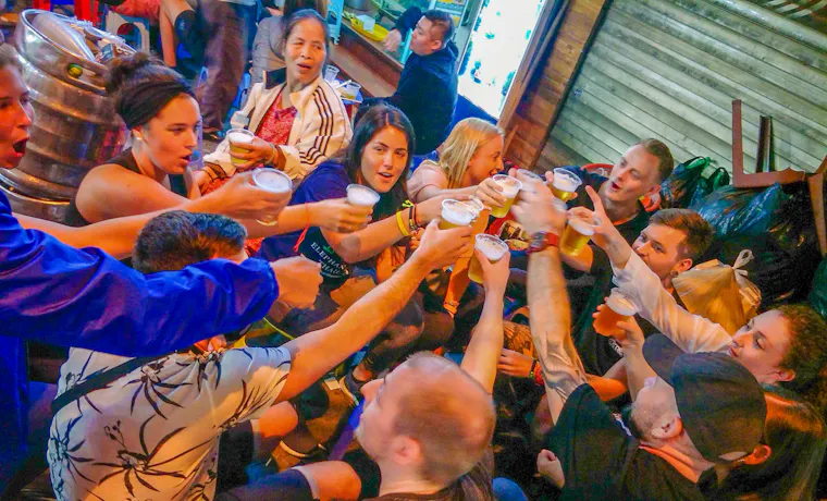 A group of happy backpackers cheers with beers during a lively night out in Hanoi.