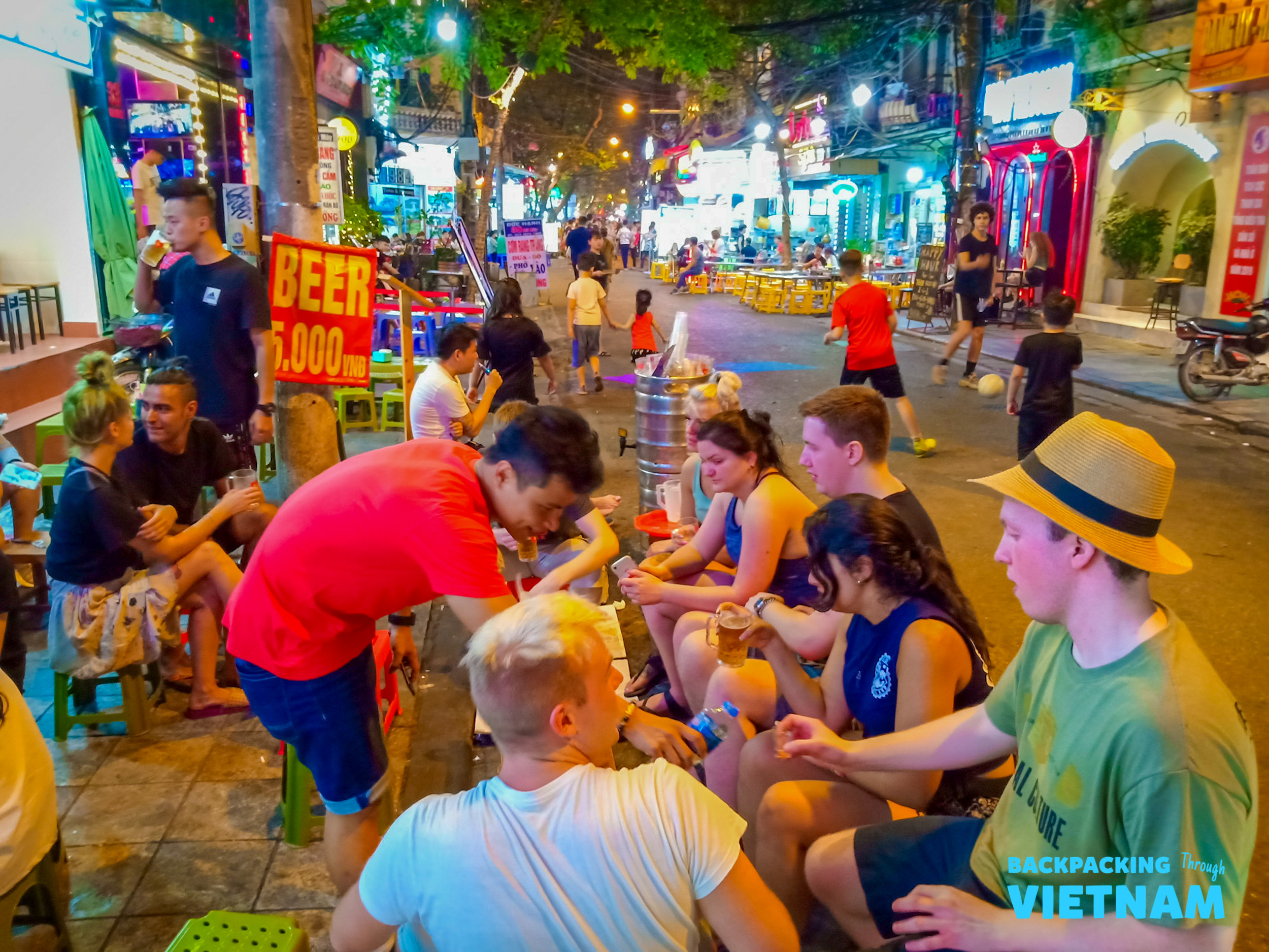 Backpackers and locals enjoy cheap beer on small stools, soaking in the lively night in Hanoi.