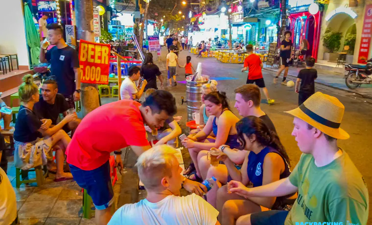 Backpackers and locals enjoy cheap beer on small stools, soaking in the lively night in Hanoi.
