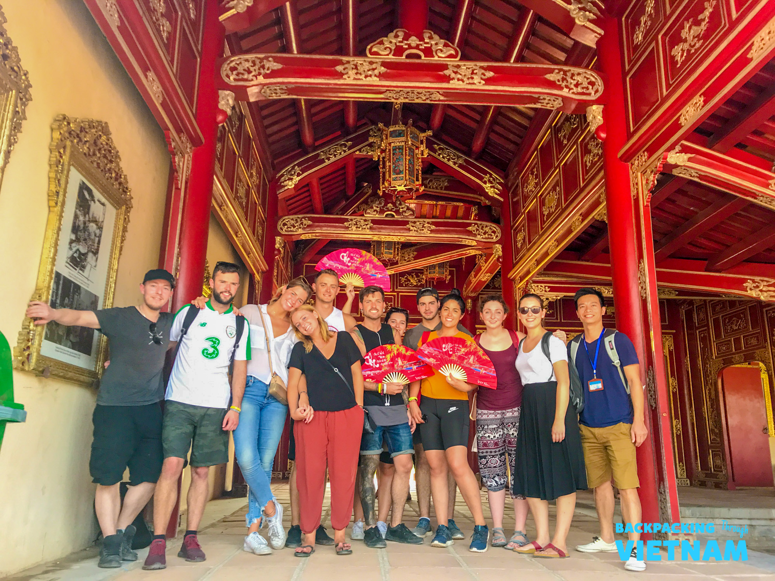 Happy backpackers pose with traditional fans inside the historic Imperial City in Hue.
