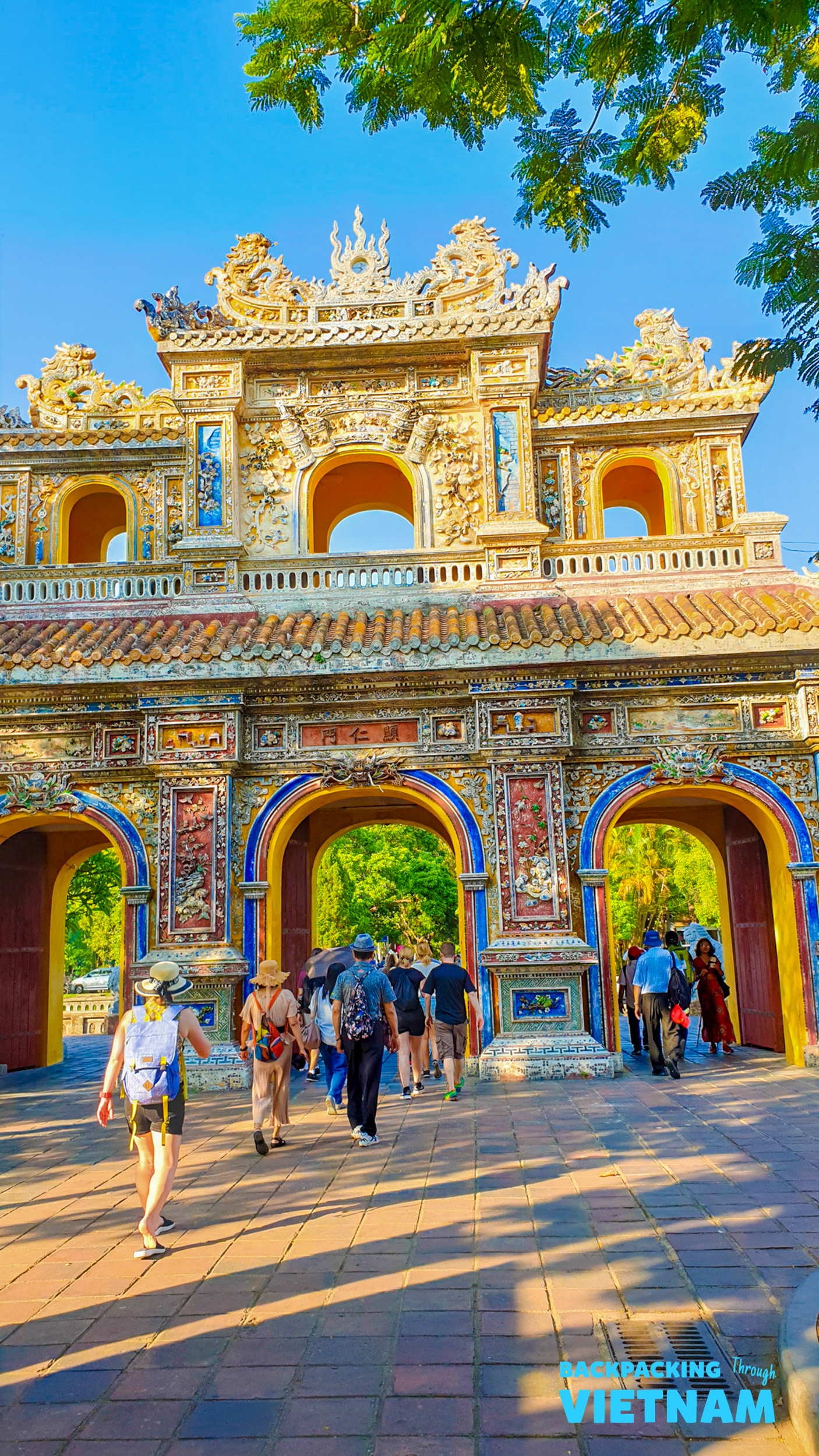 Tourists explore the grand, ornate gate of the Imperial City in Hue, Vietnam.