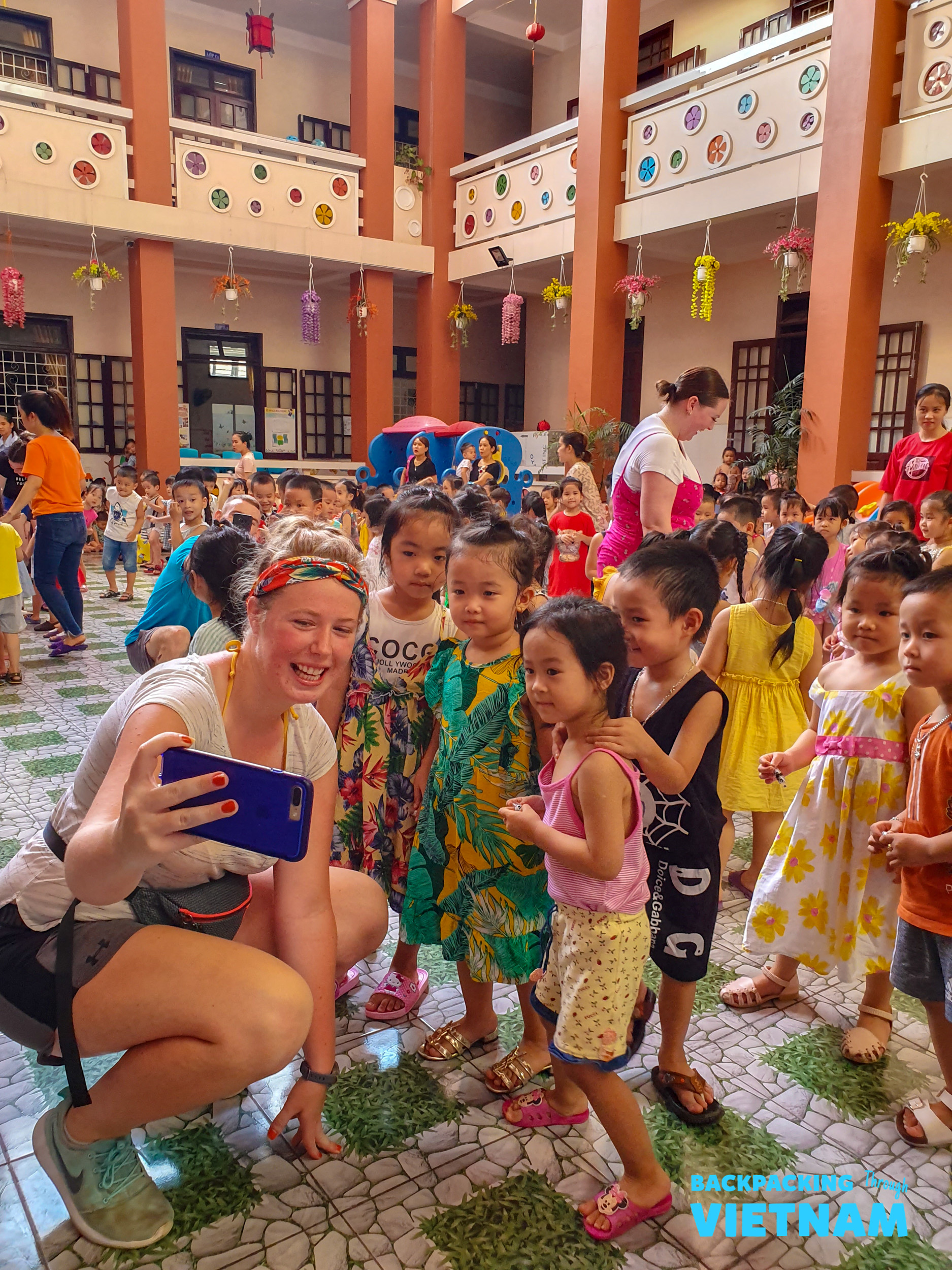 A happy volunteer takes a selfie with smiling children at a school in Hue, Vietnam.