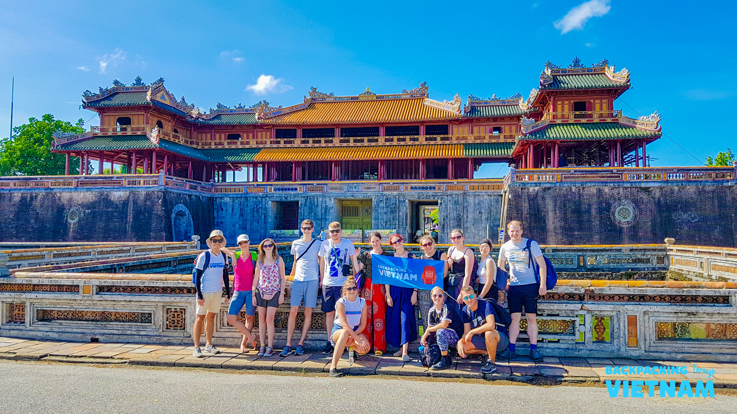 A group of happy backpackers posing in front of the magnificent Imperial City in Hue, Vietnam.