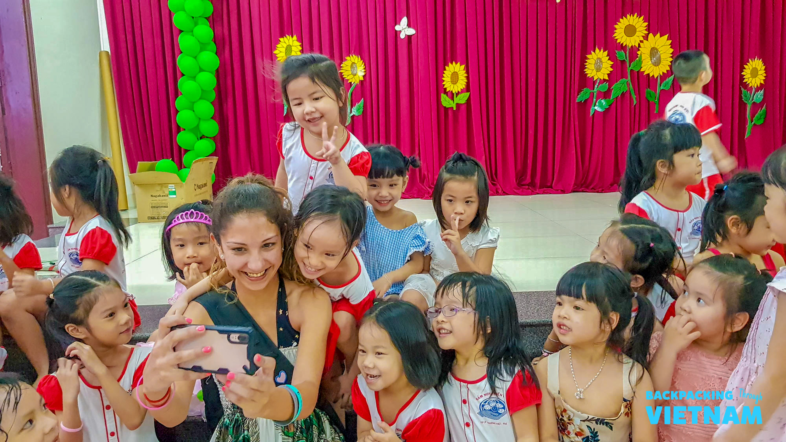 A happy volunteer takes a selfie with smiling children at a school in Hue.