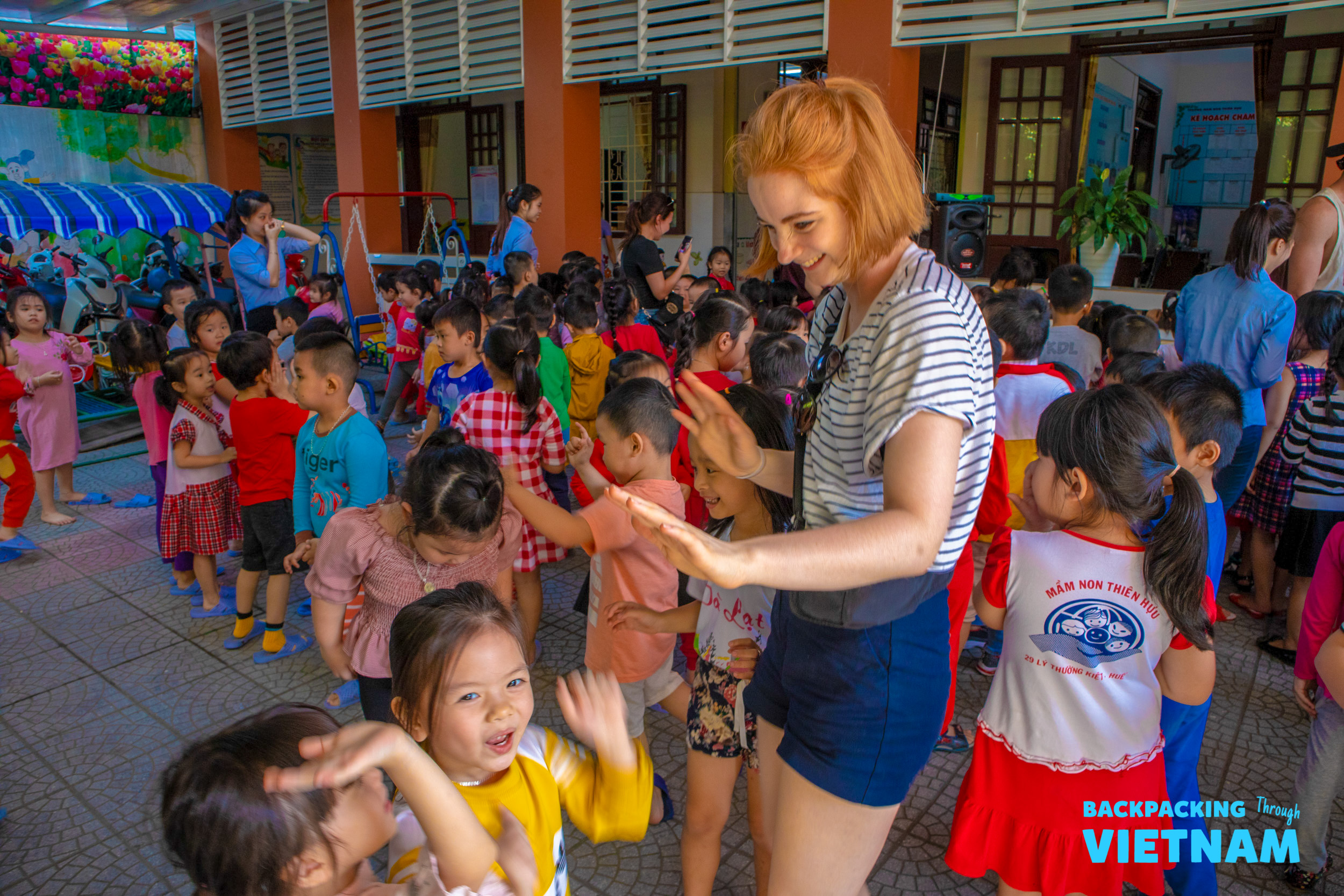 A volunteer plays a high-five game with laughing children at a school in Hue, Vietnam.