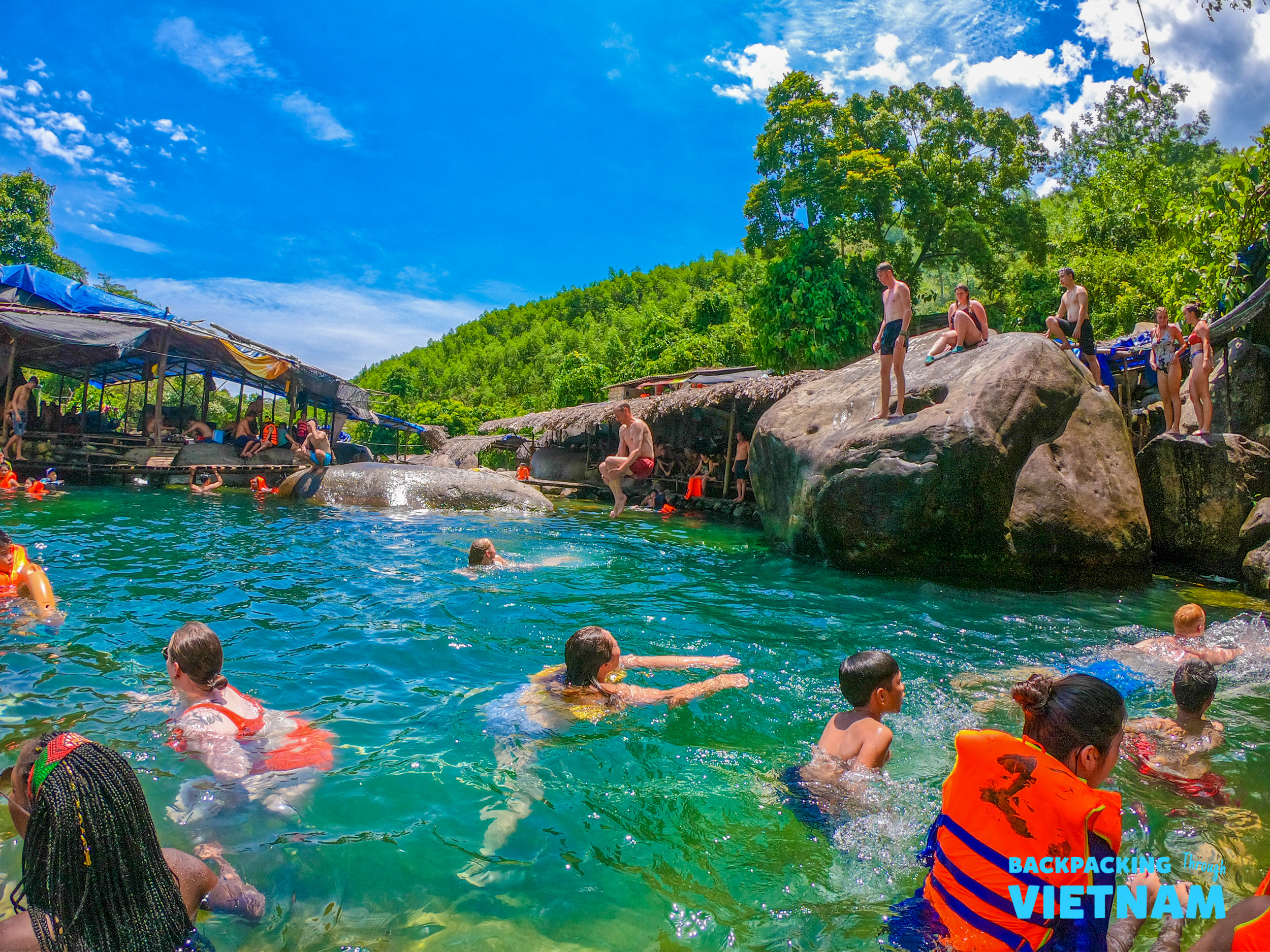 Tour participants swim and relax in a clear natural spring near the Hai Van Pass in Vietnam.