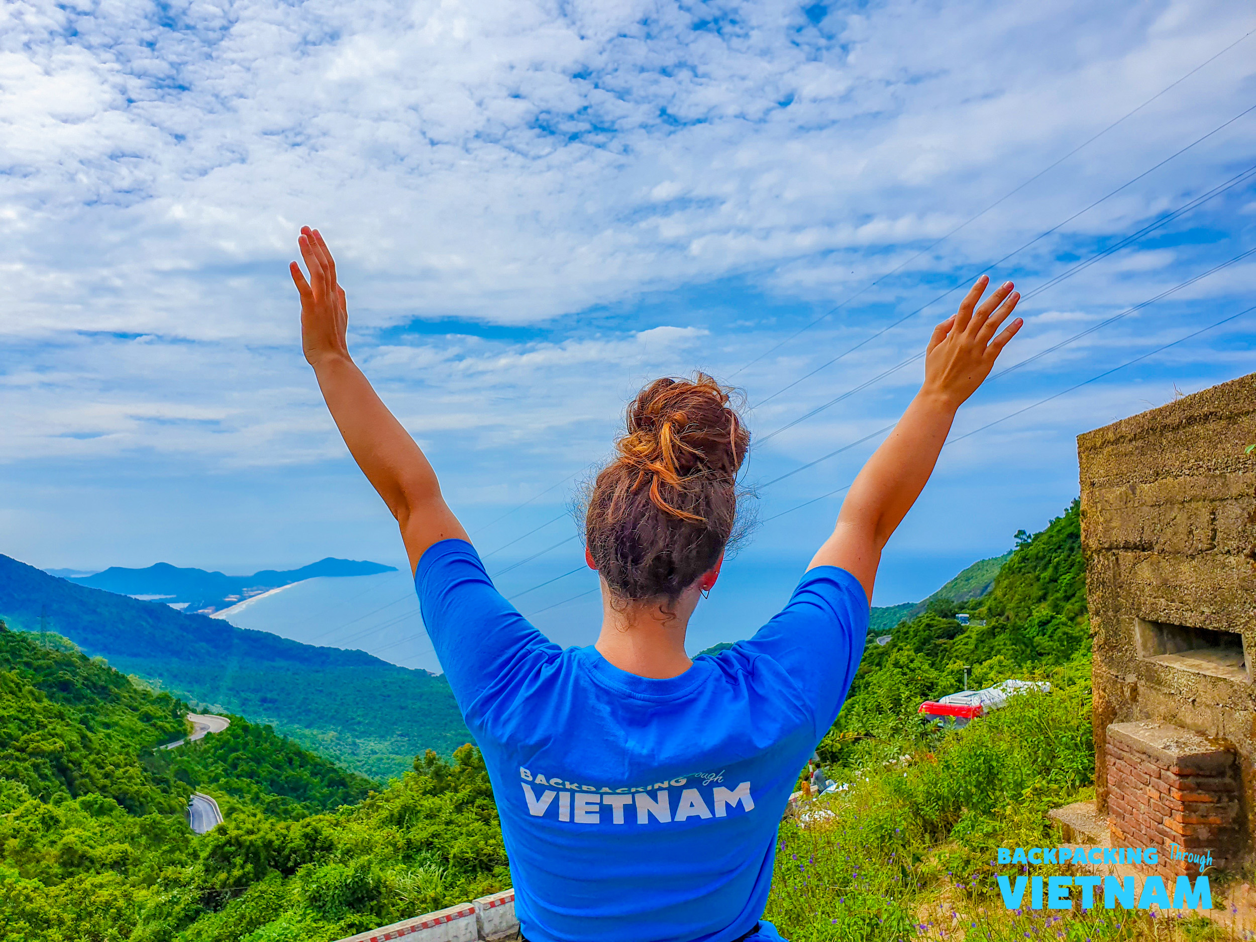 A backpacker celebrates the panoramic views of Vietnam's dramatic Hai Van Pass coastline.
