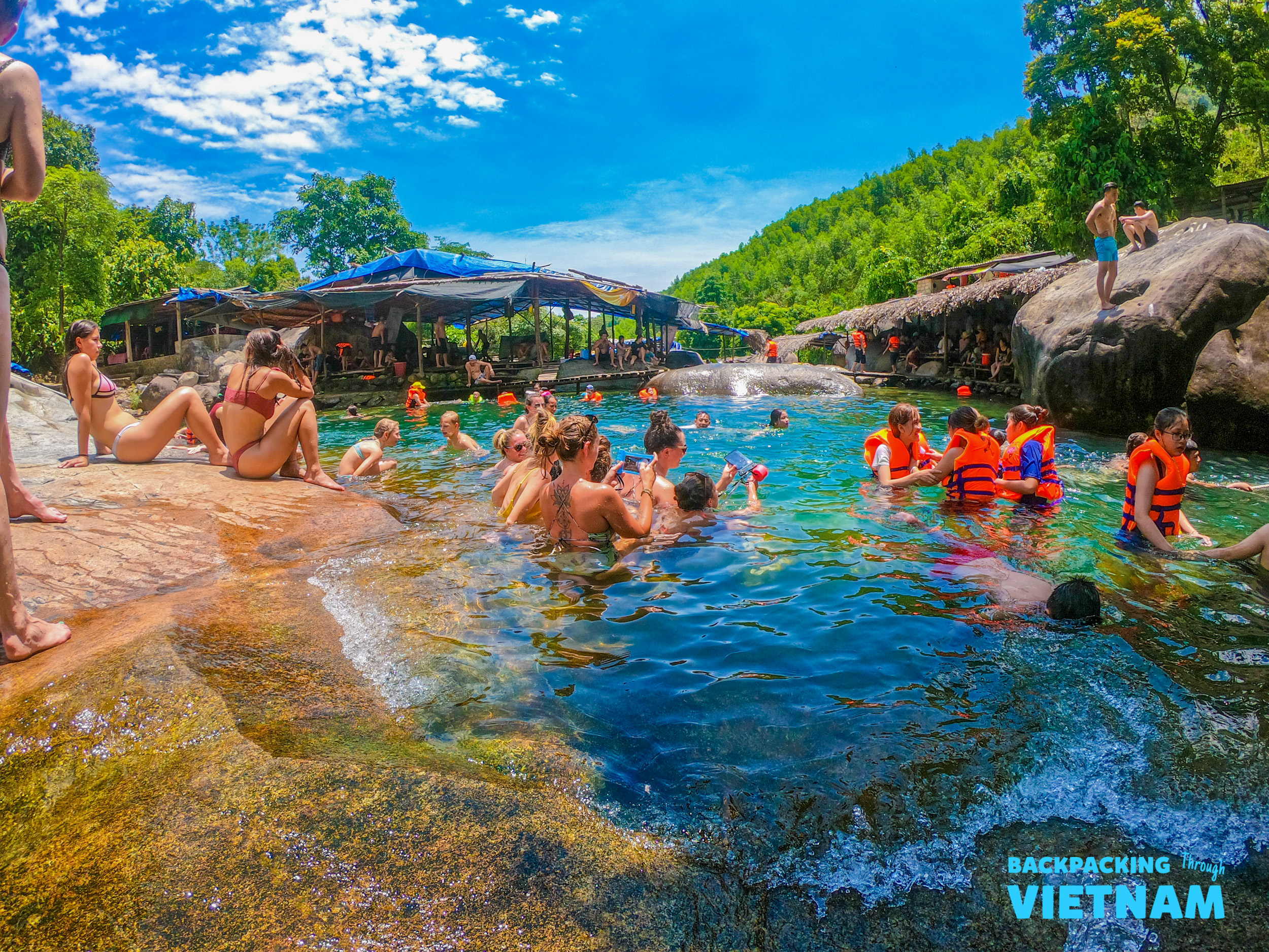 Travelers cool off and swim in a refreshing natural spring with clear blue water in Vietnam.